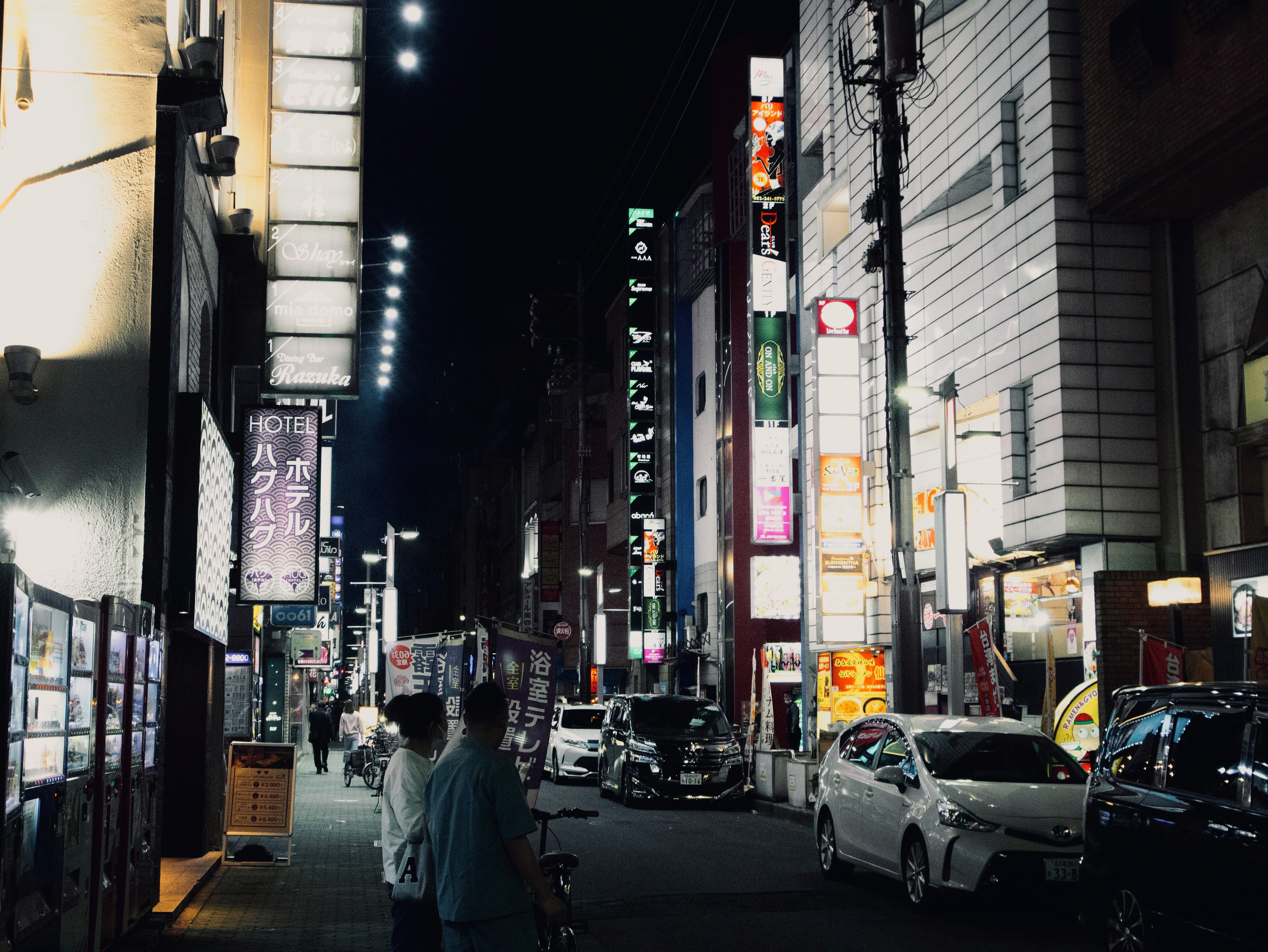 夜の街並みに賑やかなネオン看板が並ぶ通り