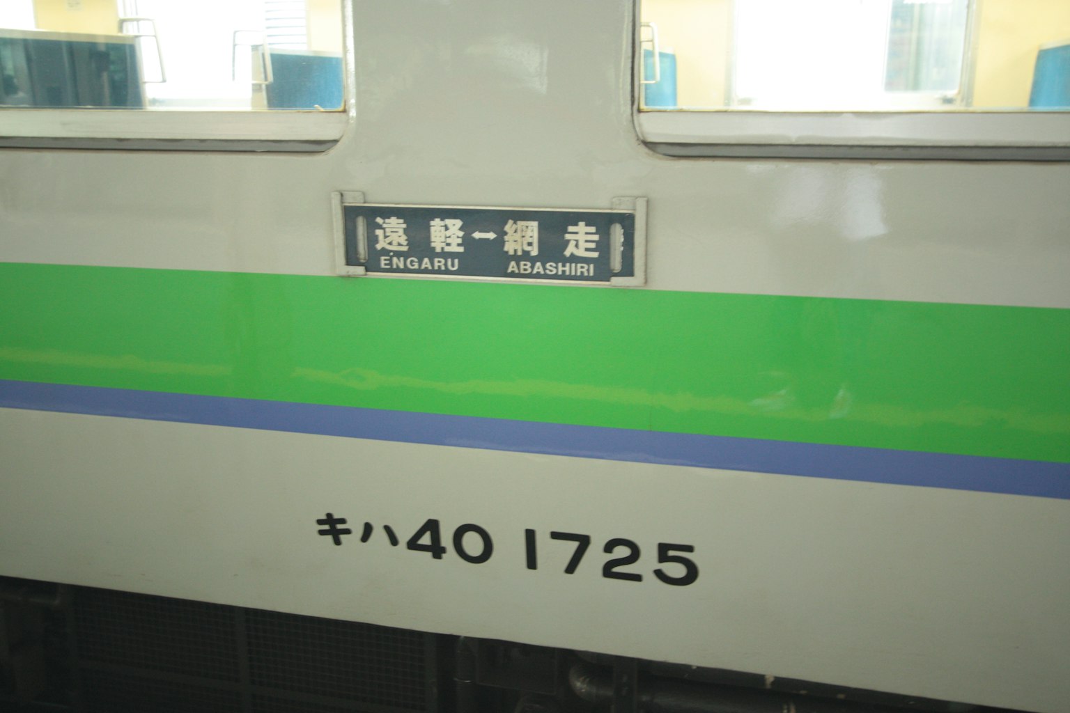 Lato di un treno con striscia verde e linea blu con segnale di ingresso passeggeri