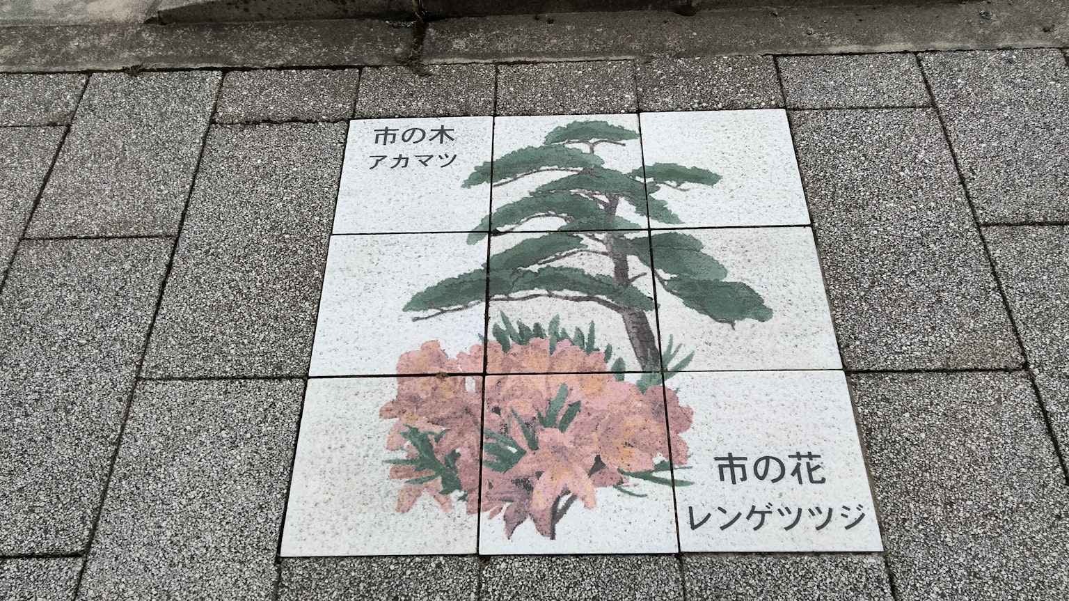 Fliesenkunst auf dem Gehweg mit rosa Blumen und einem Kiefer