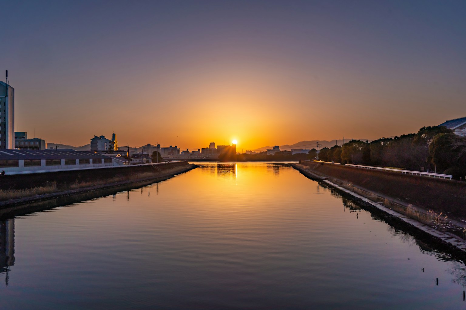 Paysage de rivière serein avec le coucher de soleil se reflétant sur l'eau et la silhouette de la ville