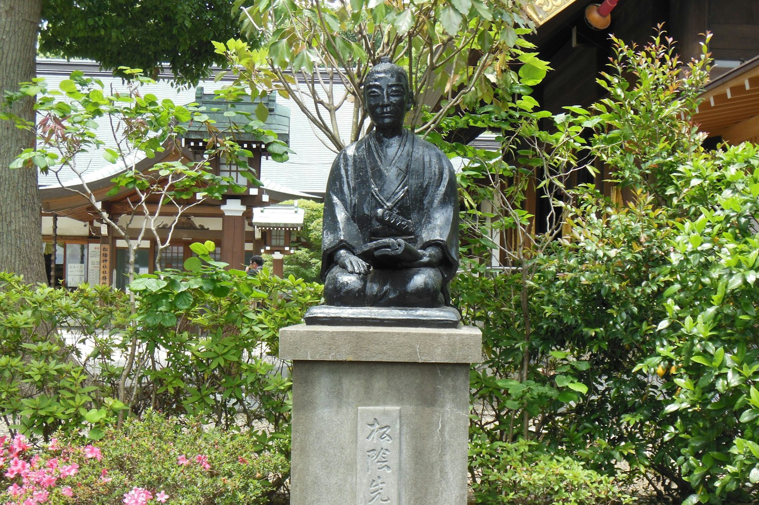 A black statue surrounded by greenery in a park