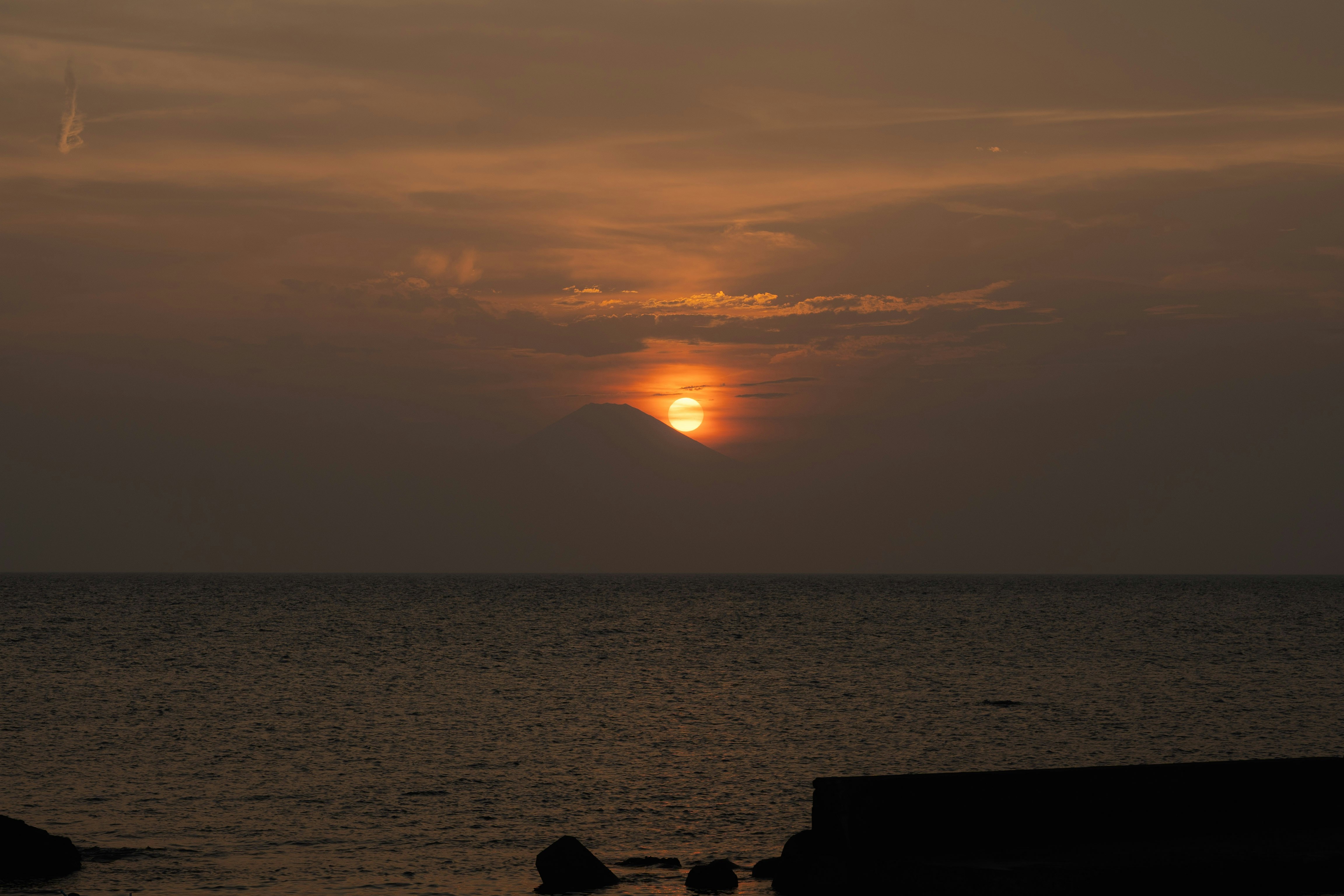 夕日に照らされた海と空に浮かぶ富士山のシルエット