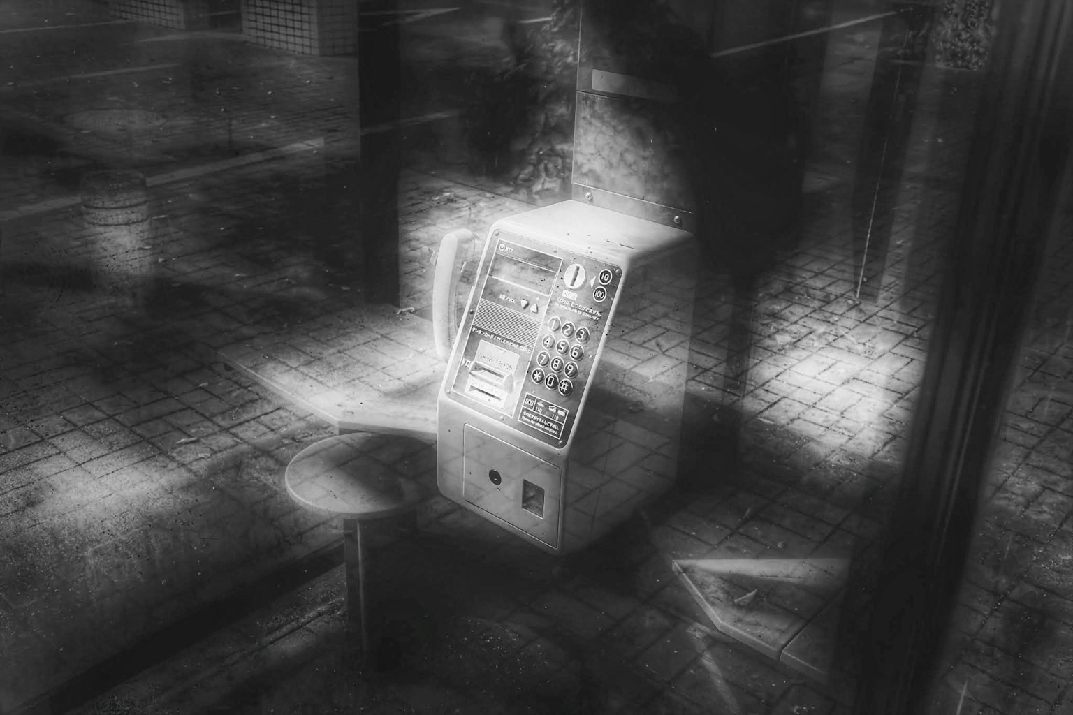 Una cabina telefónica pública en blanco y negro en un entorno poco iluminado