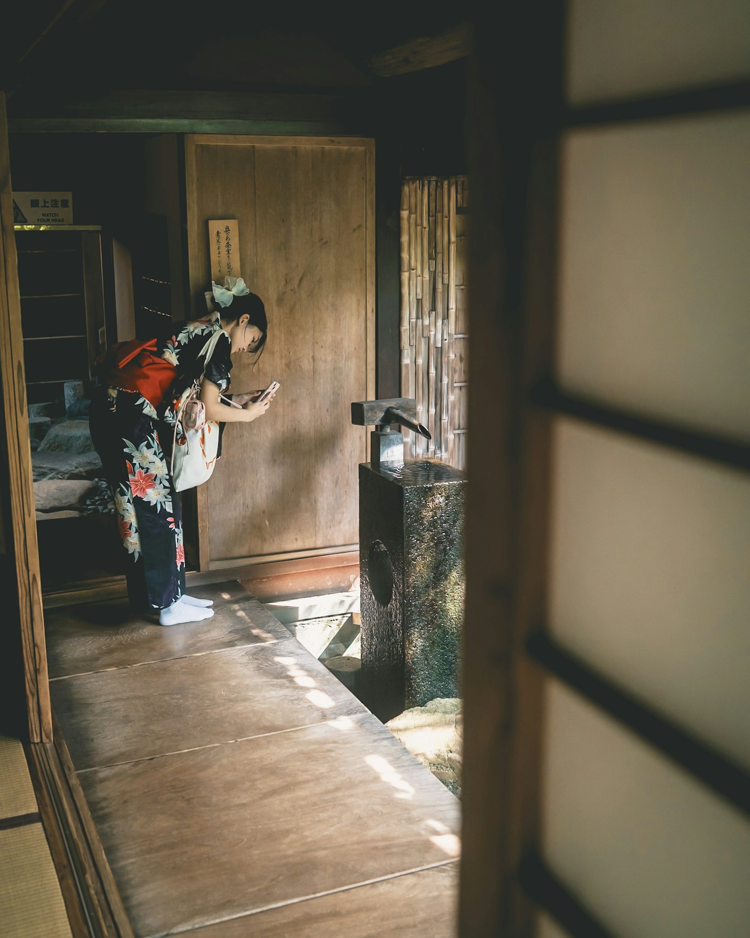 Eine Frau im Kimono steht vor einer Tür in einem traditionellen japanischen Hausinneren