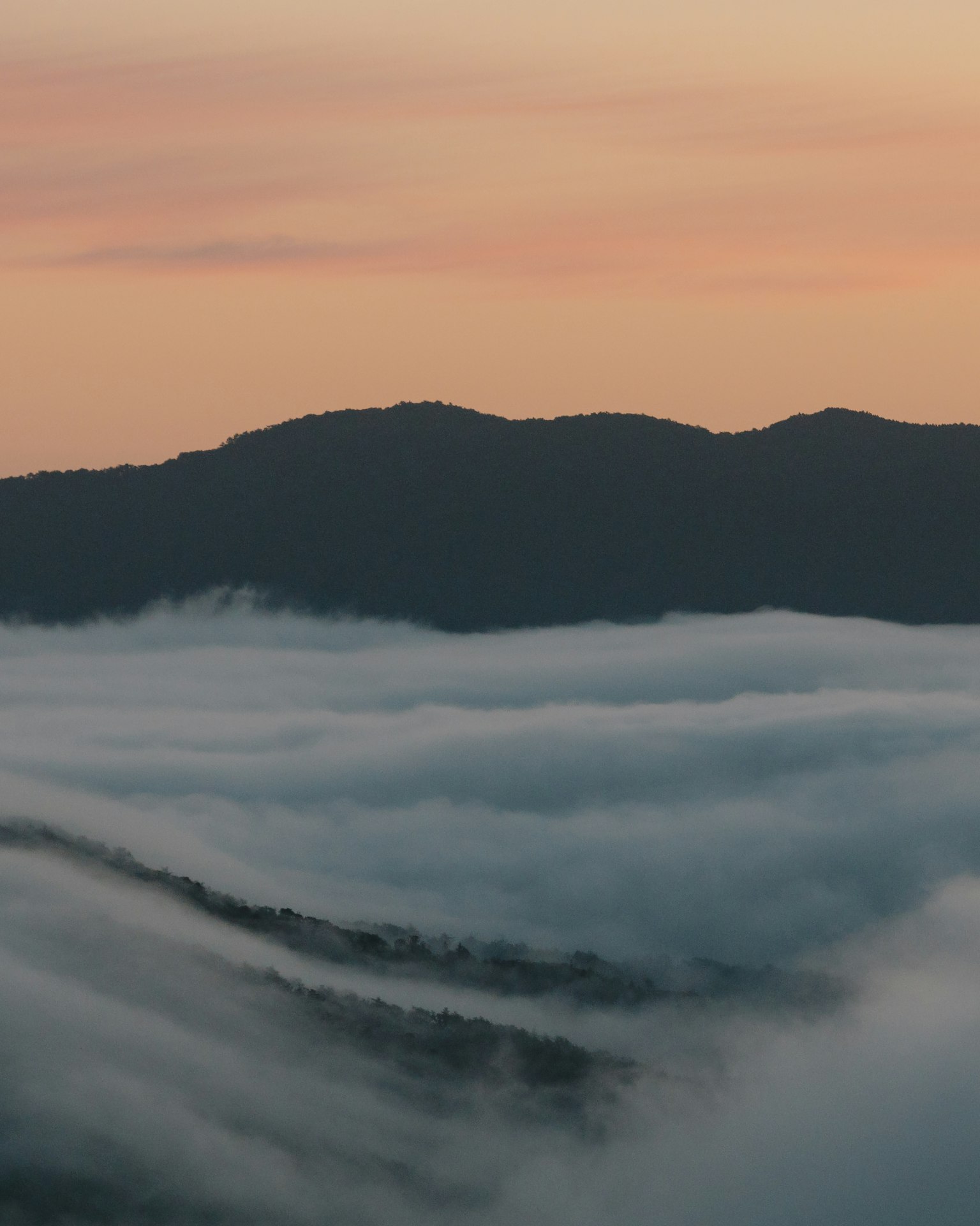 Silhouette of mountains with a fog-covered landscape at sunset