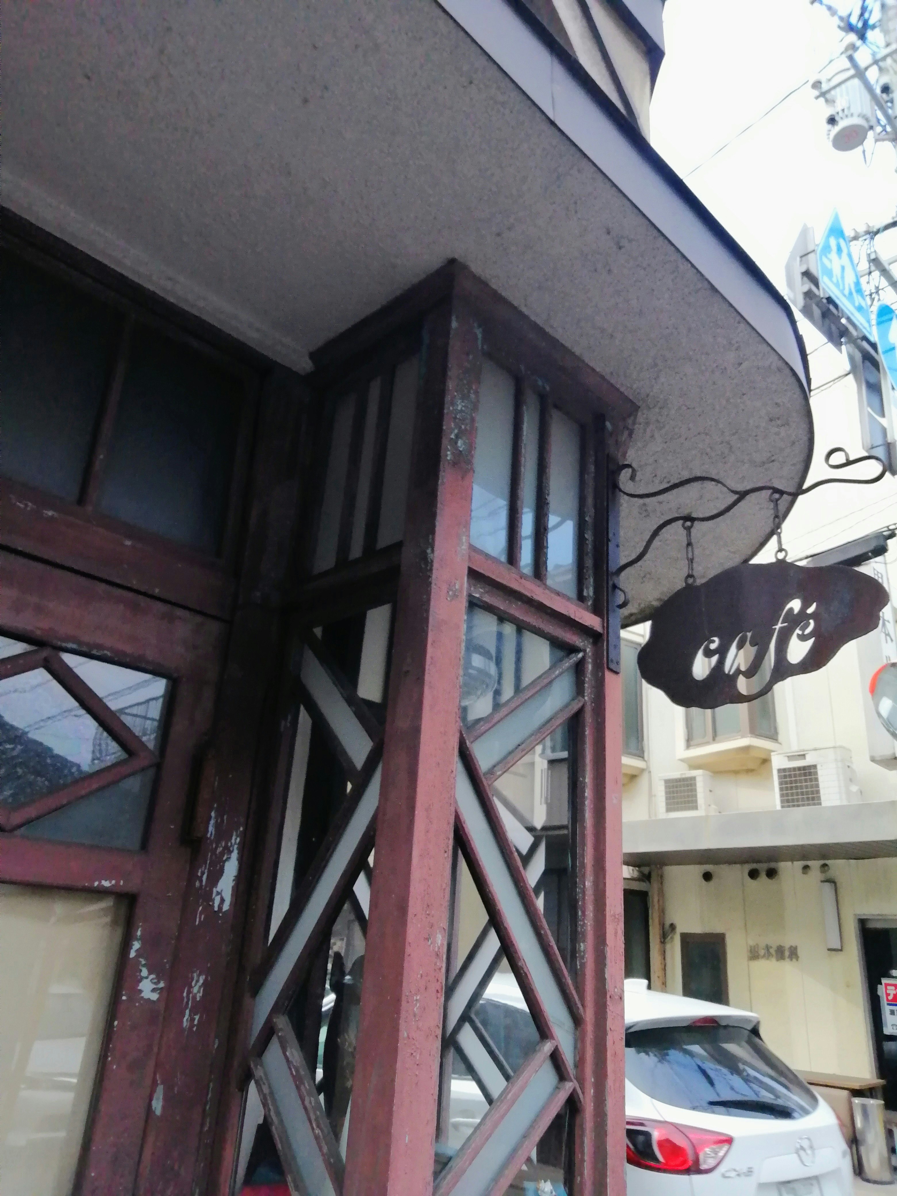 喫茶店の看板と木製の外観が見える路地の入口