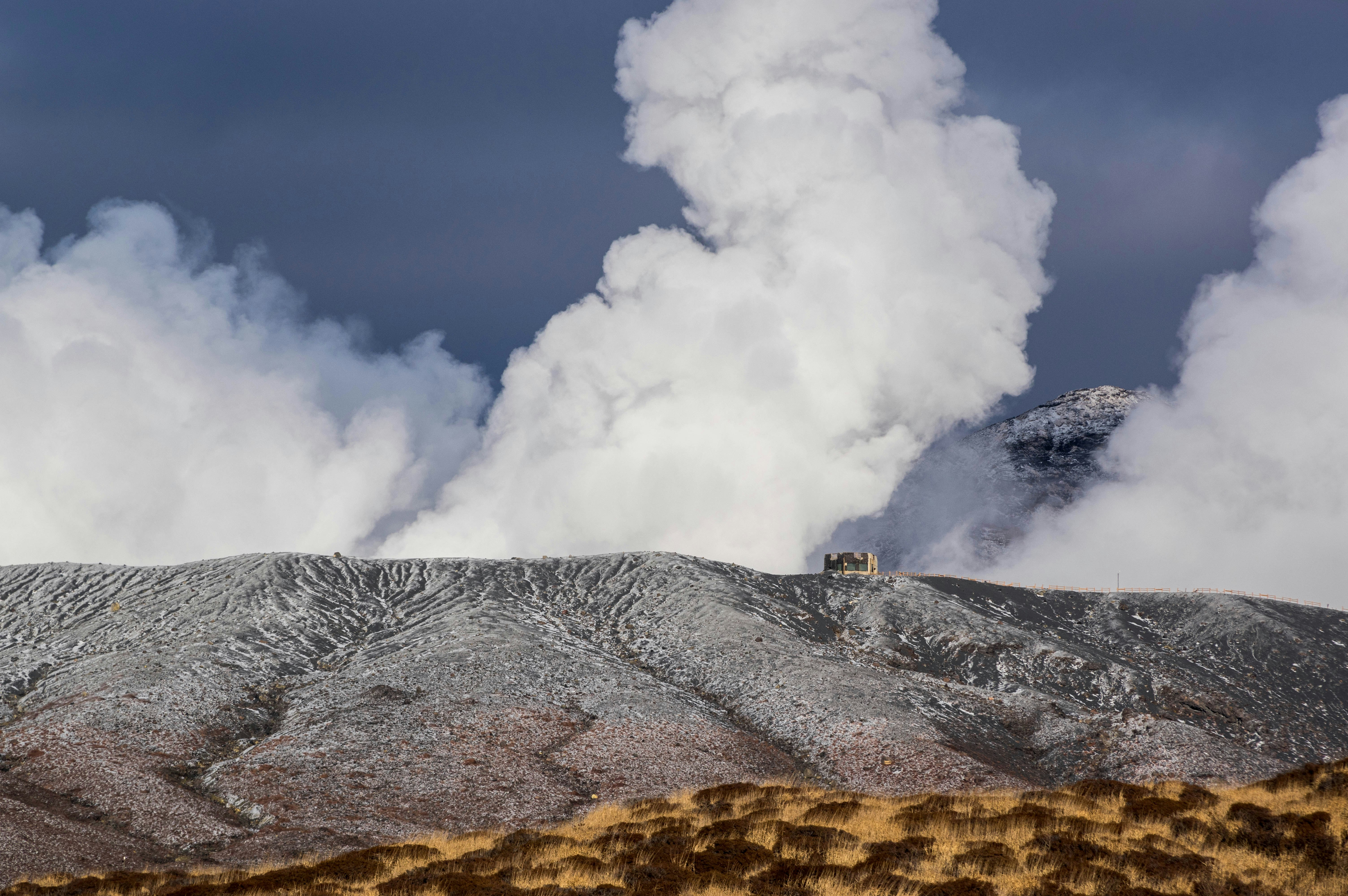 噴煙を上げる火山の山腹と空
