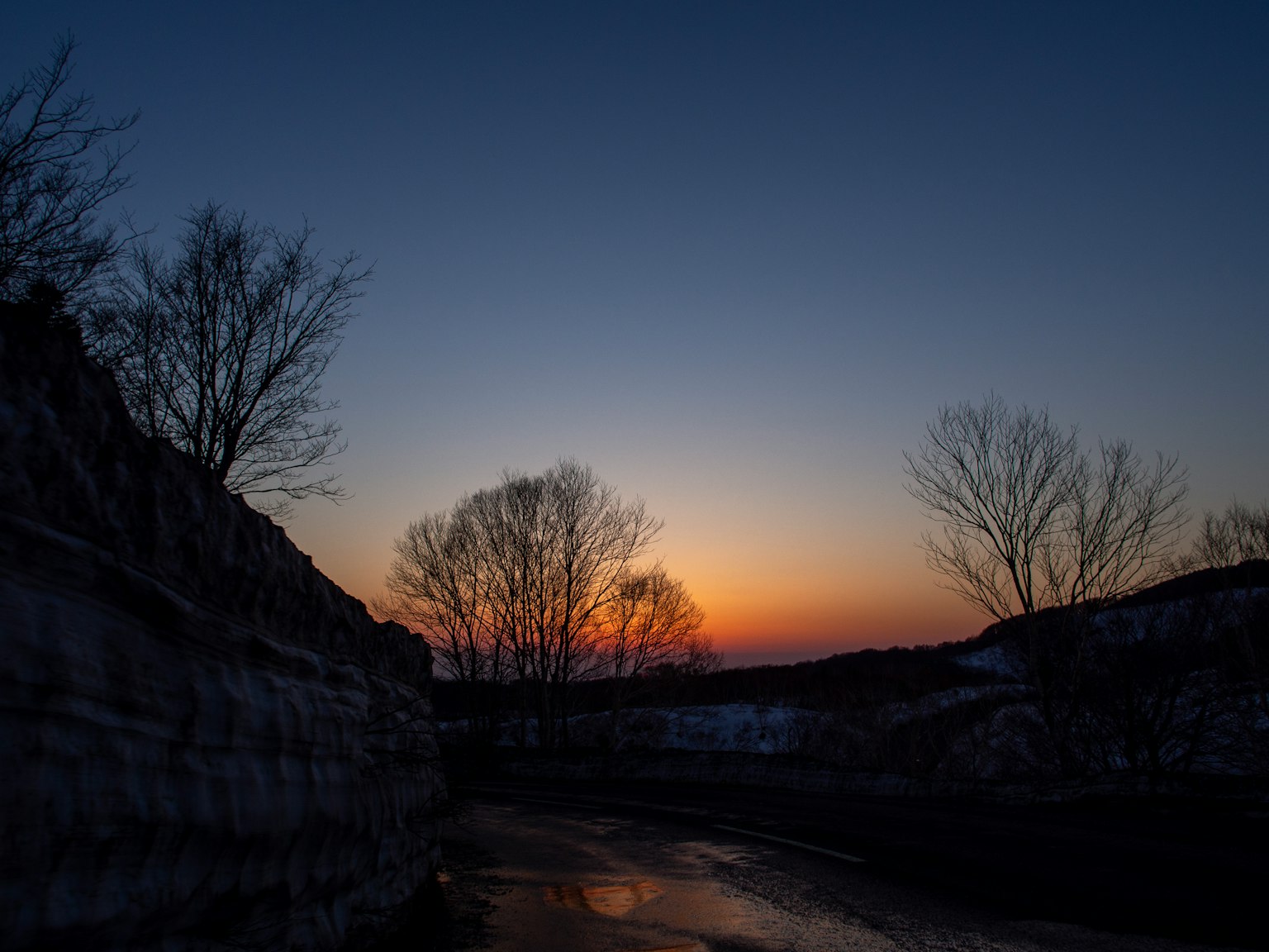 Silhouette von Bäumen und Felsen vor einem Sonnenuntergang