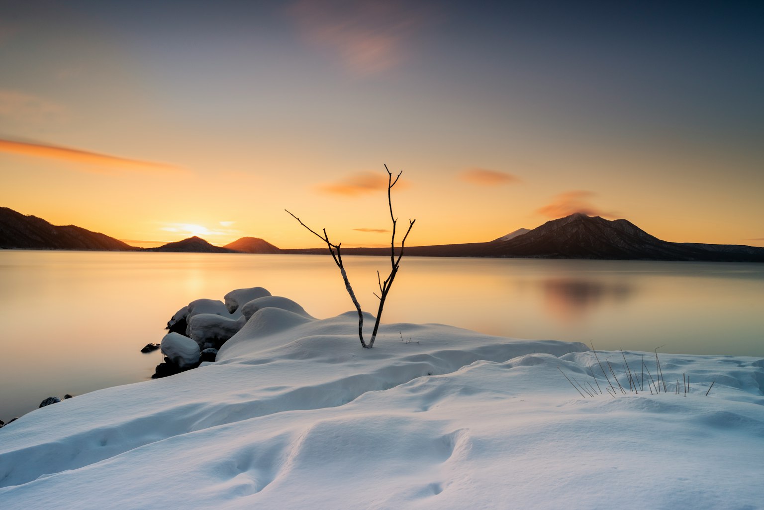 Paesaggio di riva al lago coperto di neve con cielo al tramonto