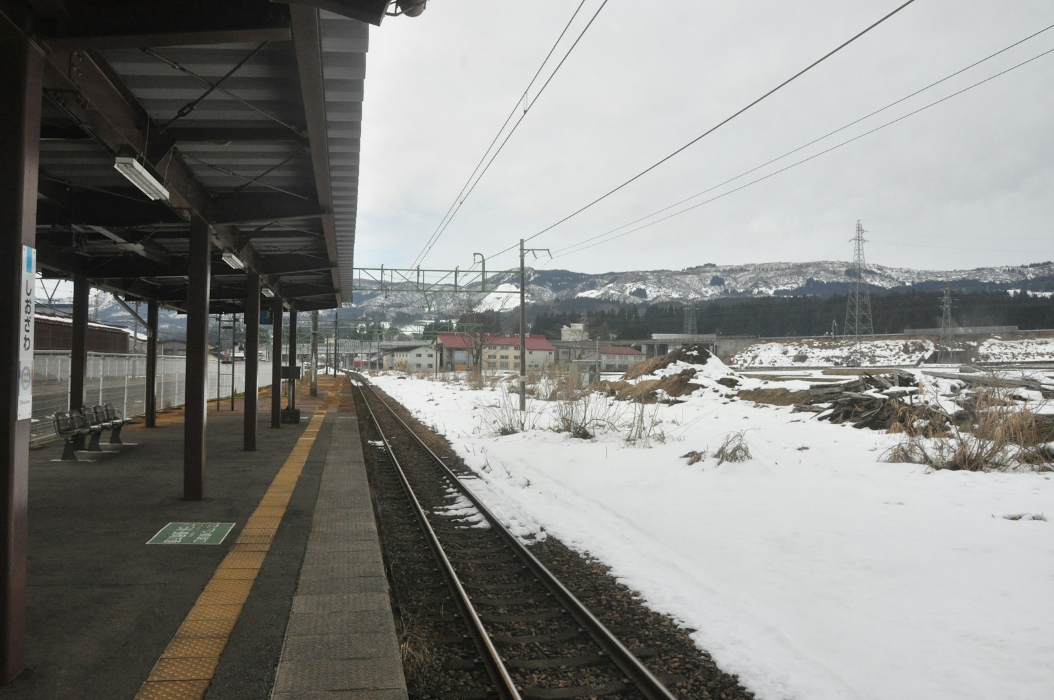 Plateforme de gare recouverte de neige avec des voies ferrées visibles