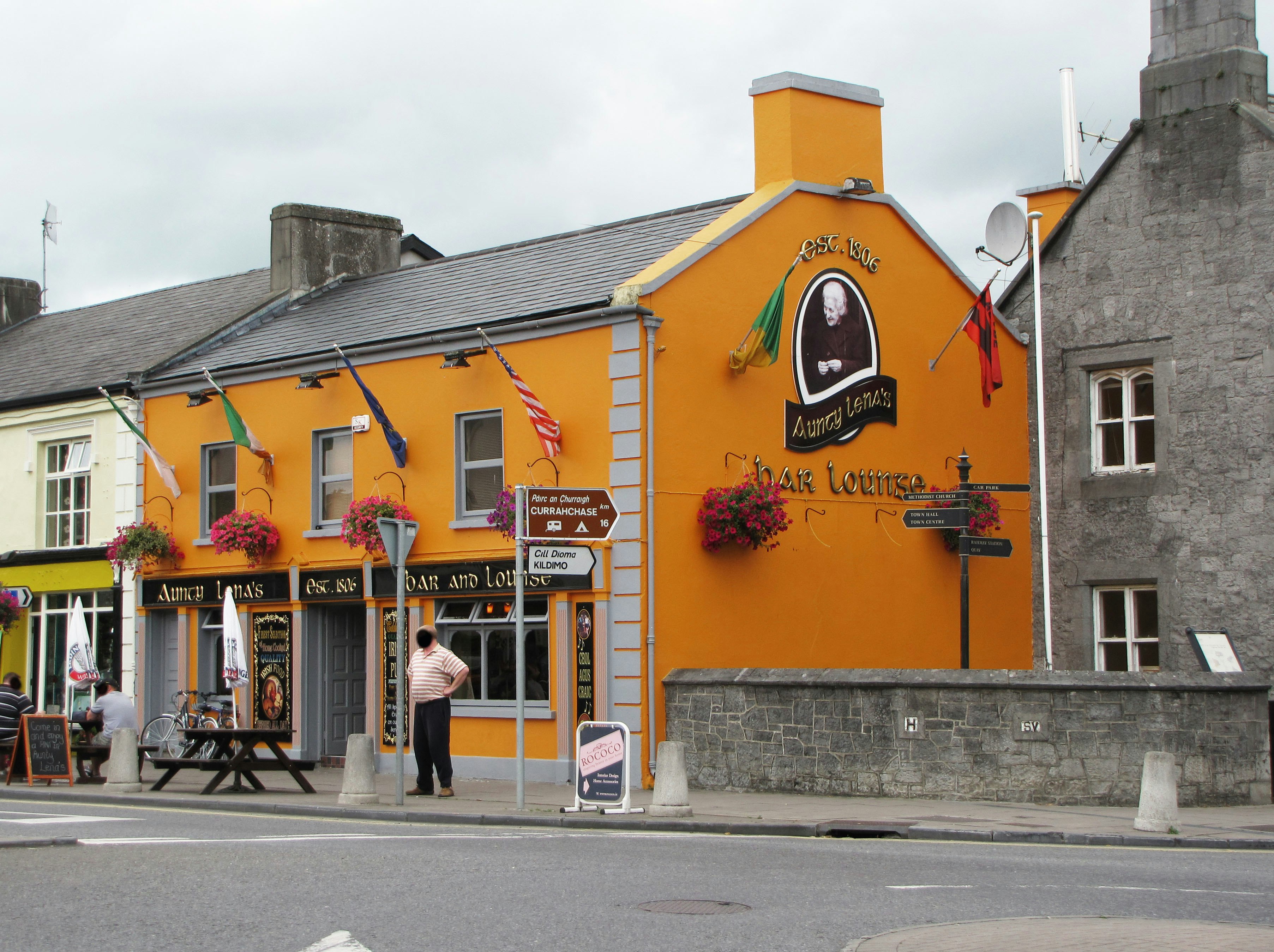 street corner with an orange storefront building and shops