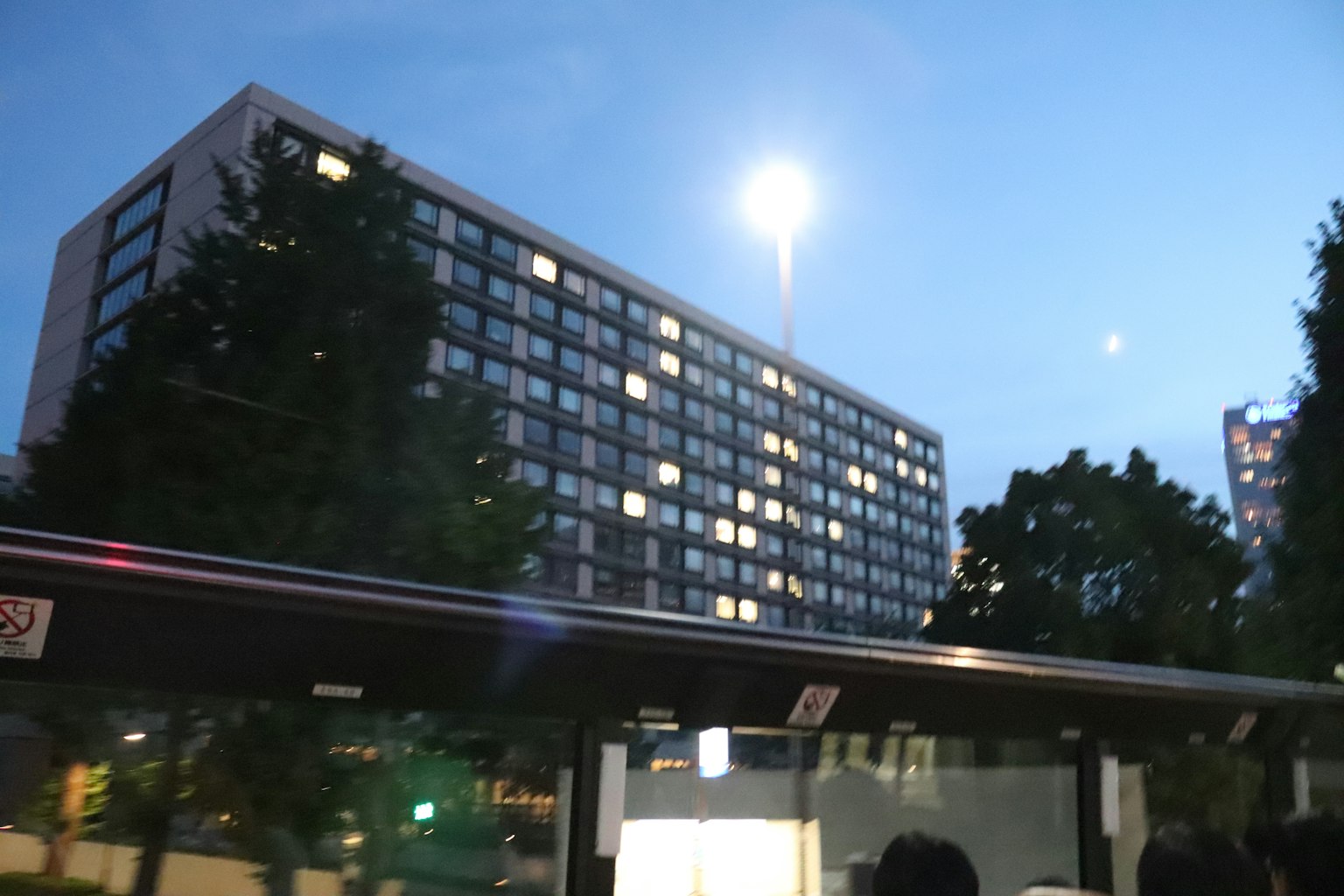 Edificio moderno iluminado por la noche con farola y cielo azul