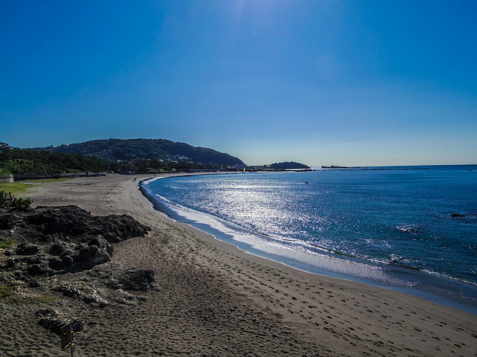Paesaggio di spiaggia panoramico con cielo azzurro e mare calmo con sabbia e rocce