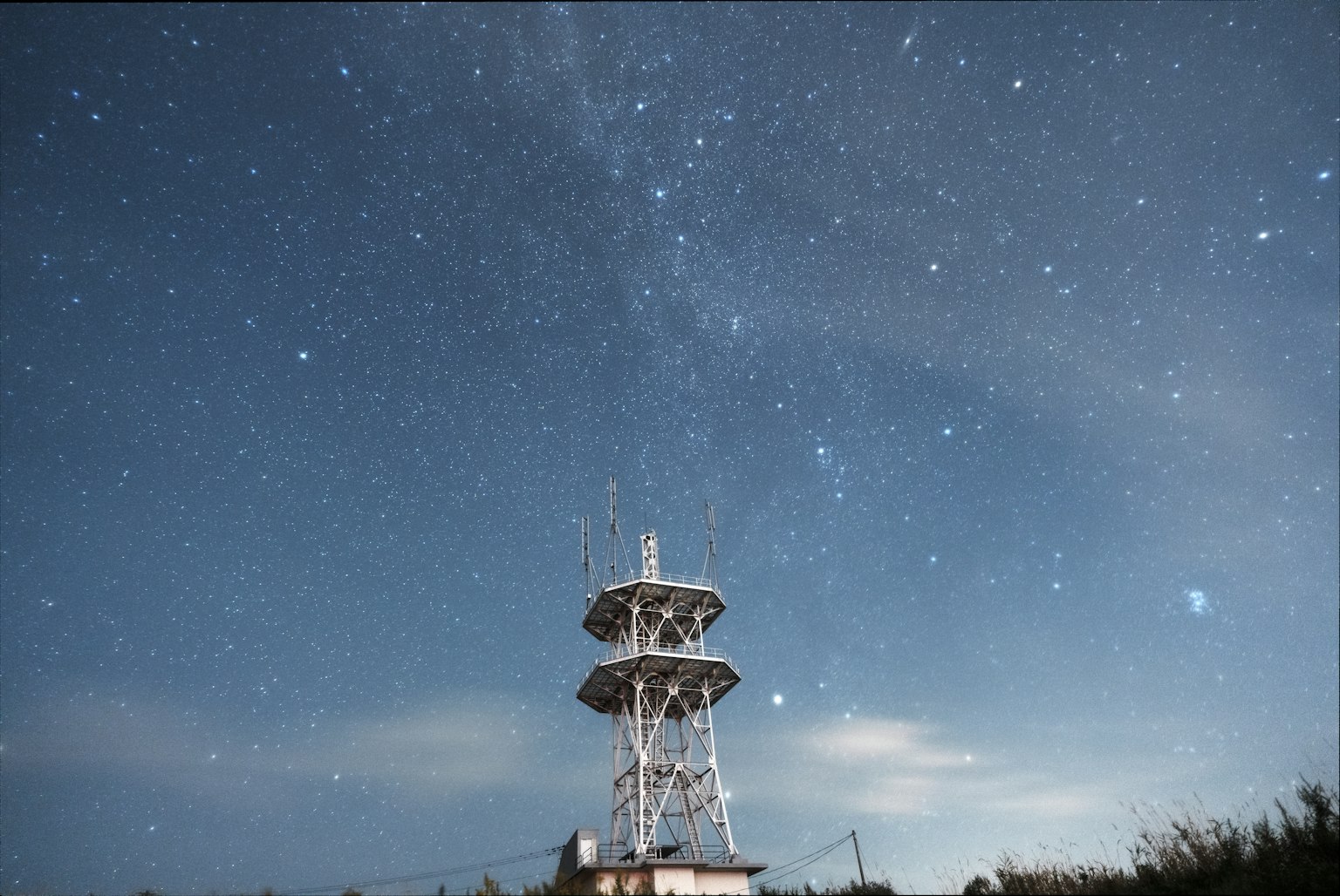 星空の下に立つ通信塔の夜景