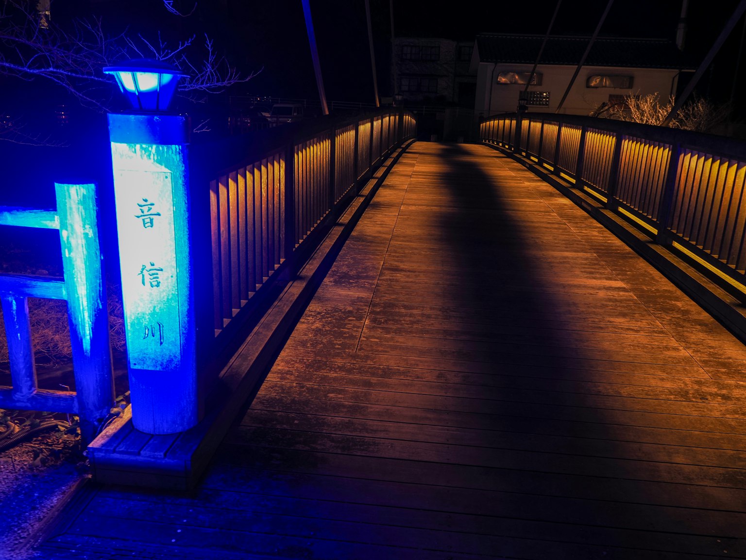 ทิวทัศน์ยามค่ำคืนของสะพานไม้ที่มีไฟสีน้ำเงินส่องสว่าง