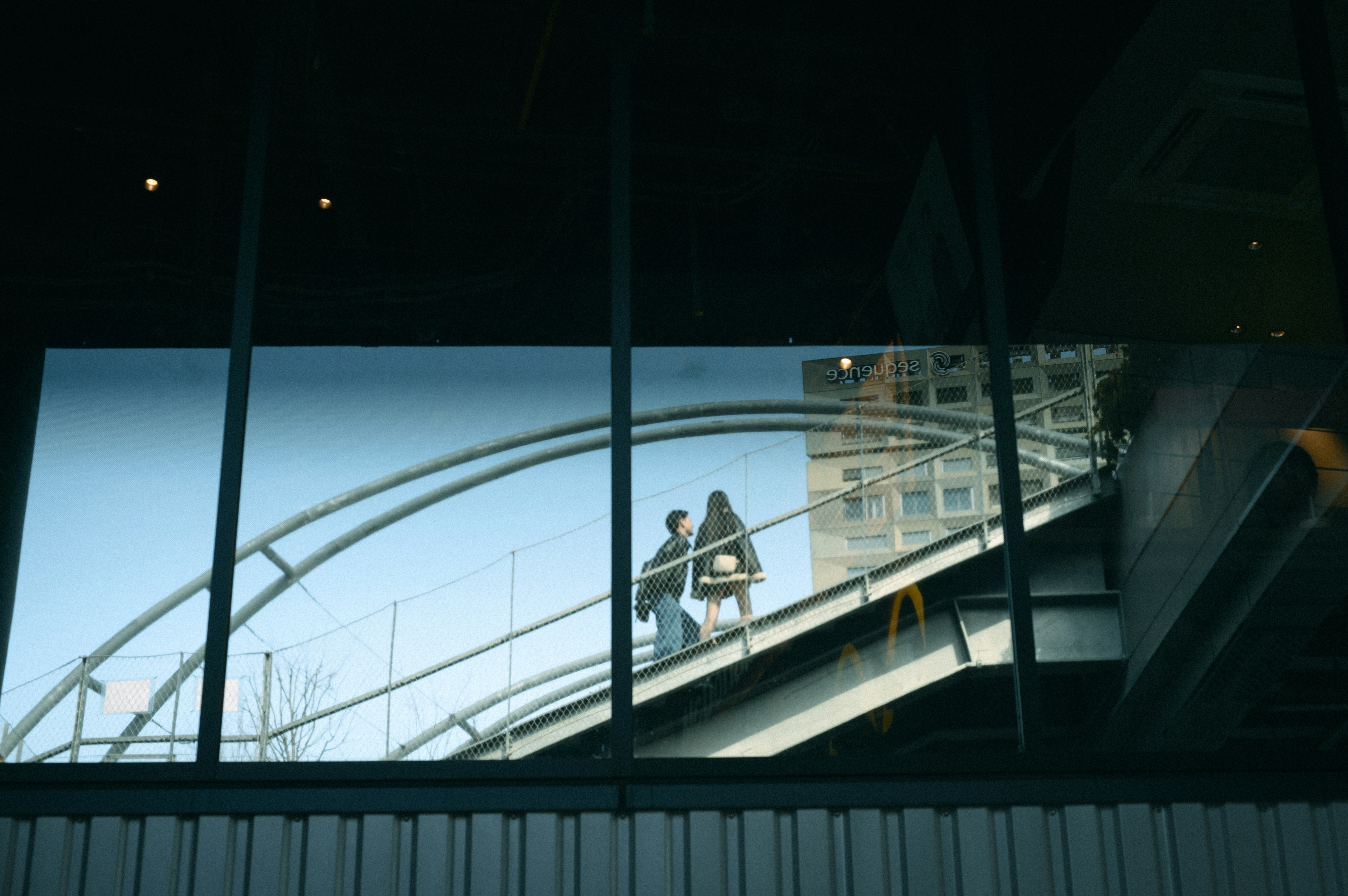 Reflet d’un pont piéton et de personnes vus à travers une vitre