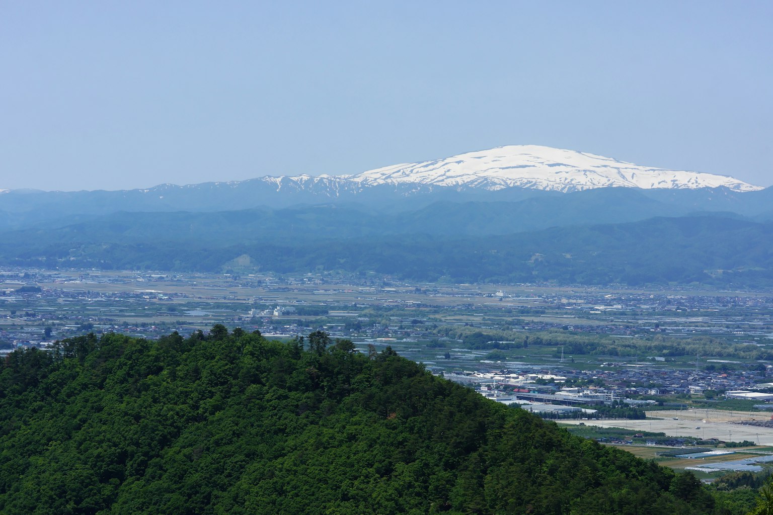 Scenic view of a snow-capped mountain and green hills
