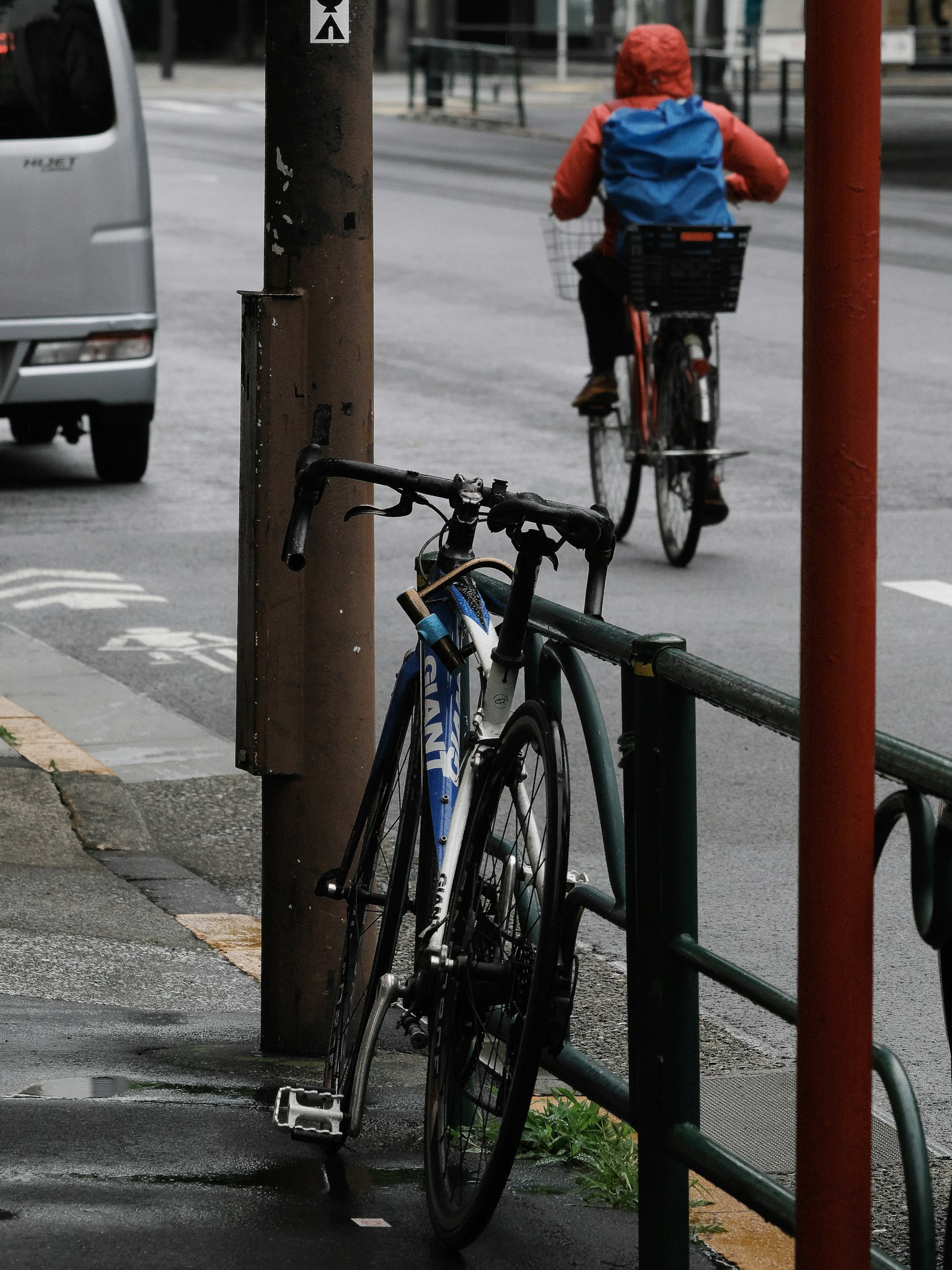 Un vélo garé près d'une rue avec un cycliste portant un imperméable
