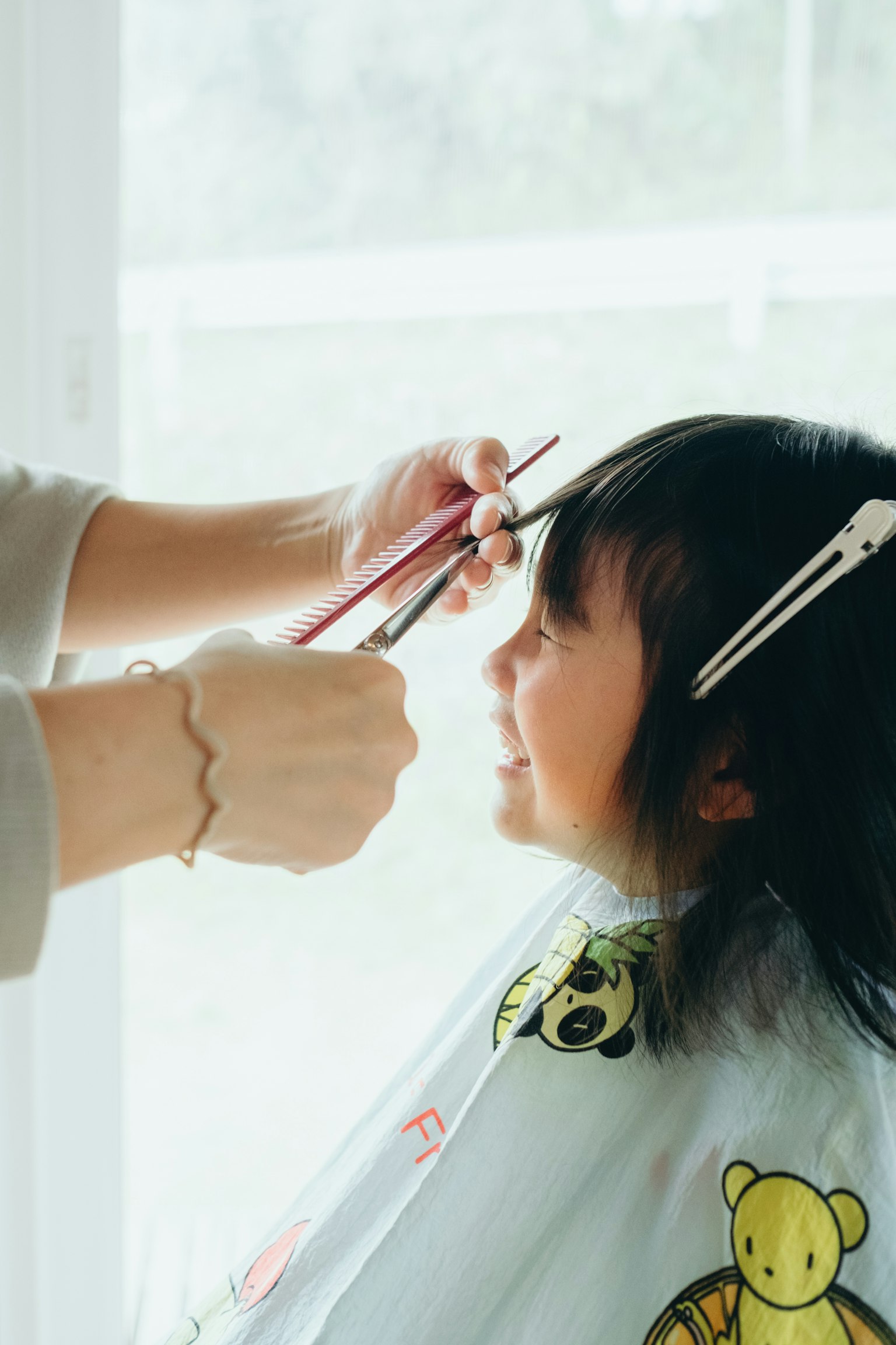Ein Friseur schneidet die Haare eines Kindes mit einem Lächeln auf dem Gesicht des Kindes