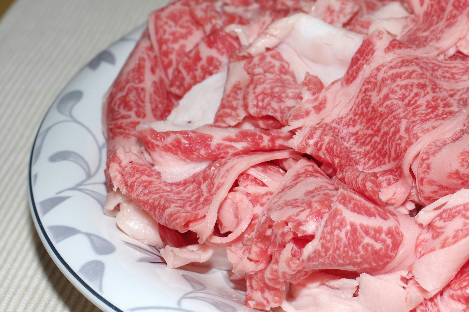 Irisan daging Wagyu tipis dengan marmer yang indah disusun di atas piring