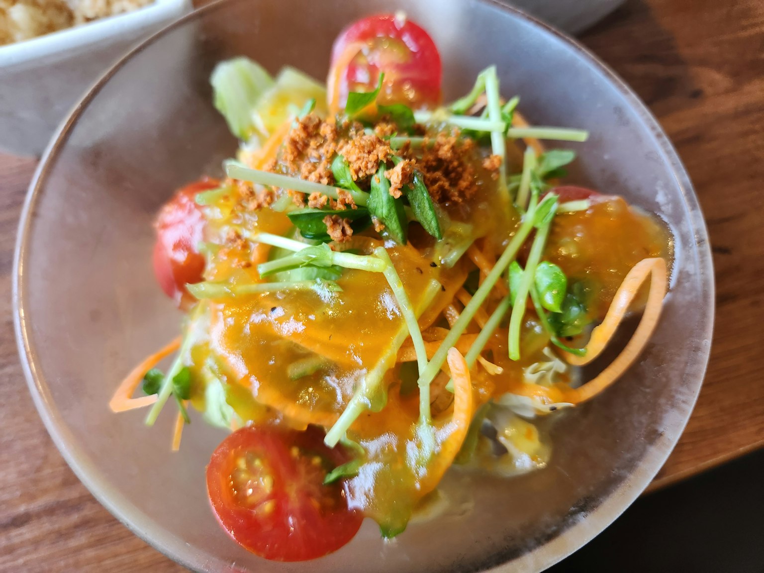 Une salade colorée avec des légumes variés et des tomates surmontée d'un garniture croustillante