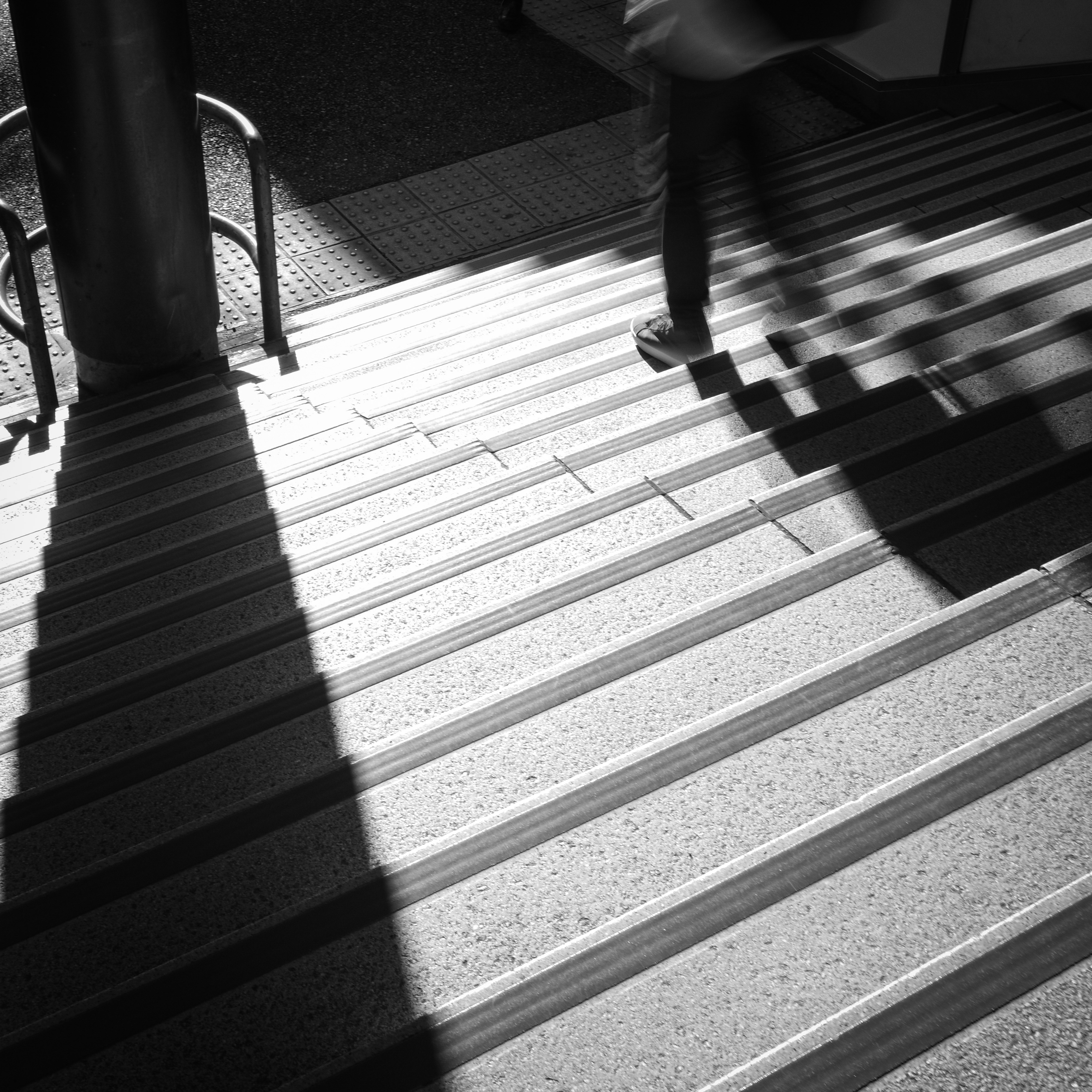 Crosswalk stripes with pedestrians’ shadows on the sidewalk