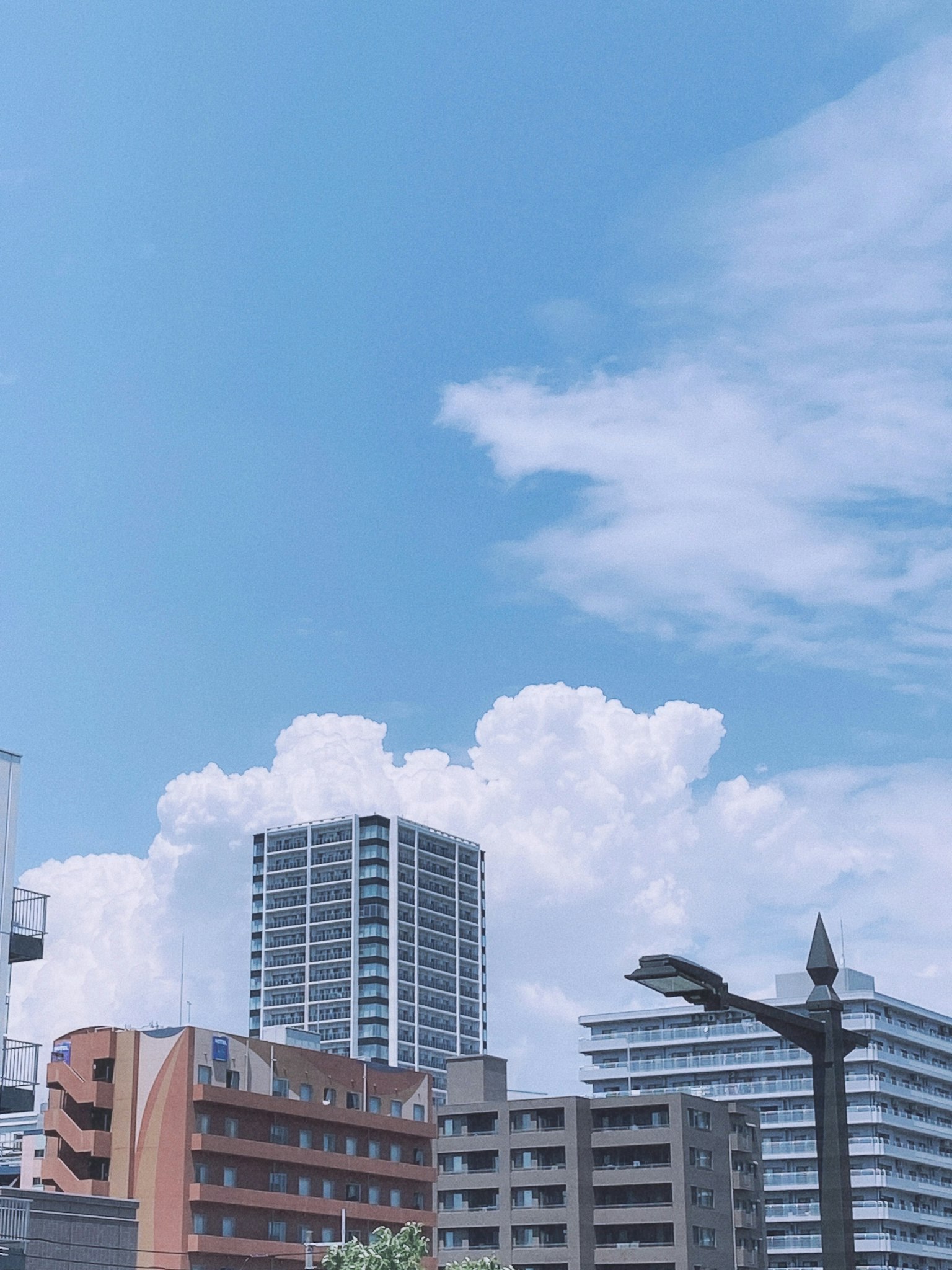 ทัศนียภาพเมืองมีตึกสูงอยู่ใต้ท้องฟ้าสีฟ้ากับเมฆสีขาว