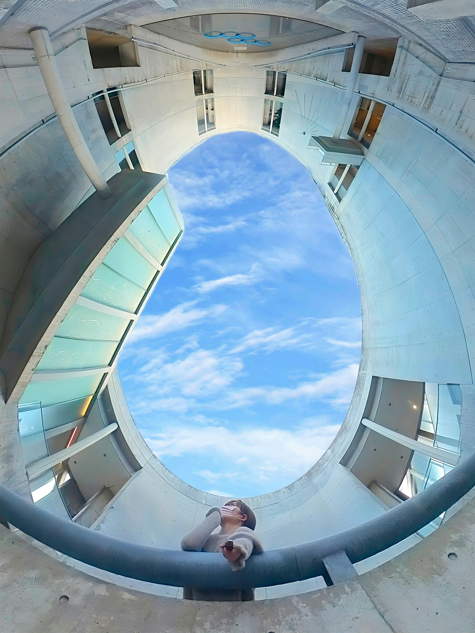 一個人站在圓形建築內，頭頂是藍天