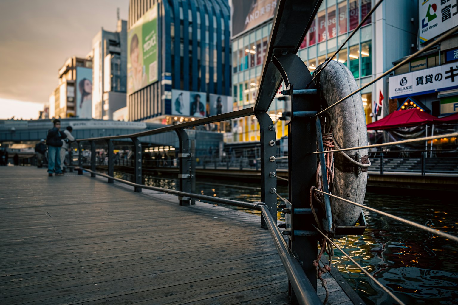 Metal railing along a riverside walkway with cityscape