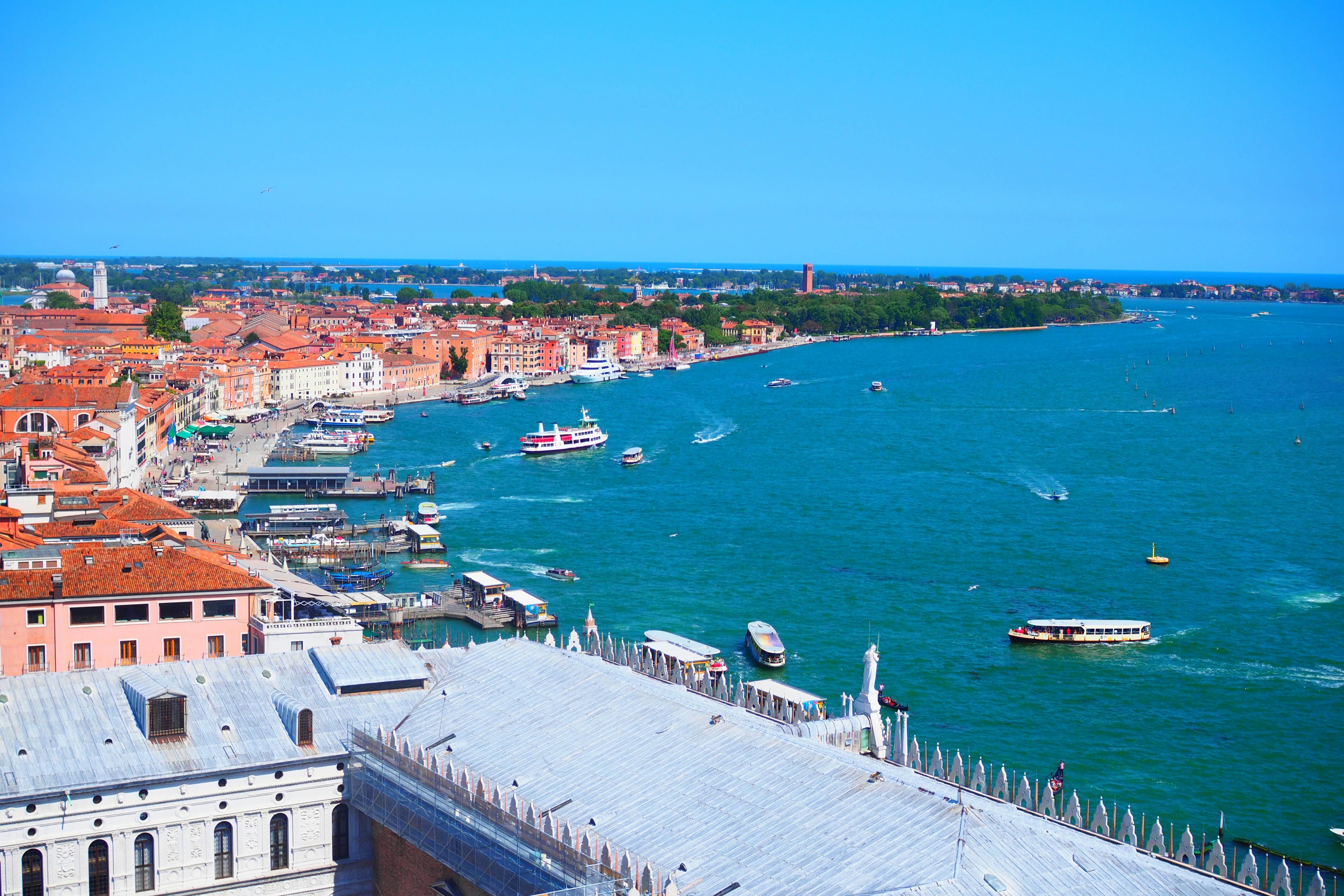 a panoramic view over a seaside harbor and red-roofed cityscape