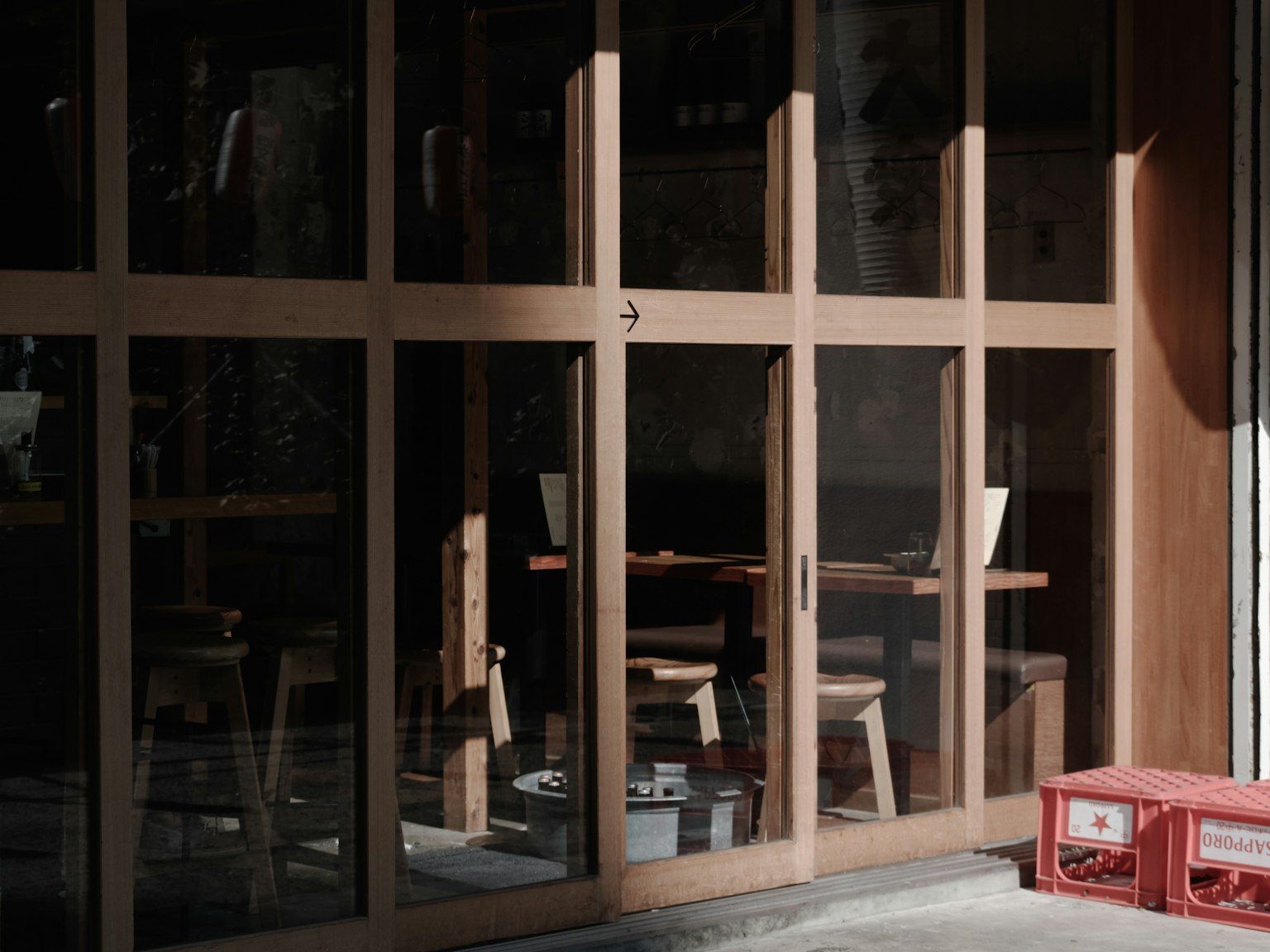 Extérieur de café avec des portes en verre à cadre en bois montrant des tables et des chaises à l'intérieur