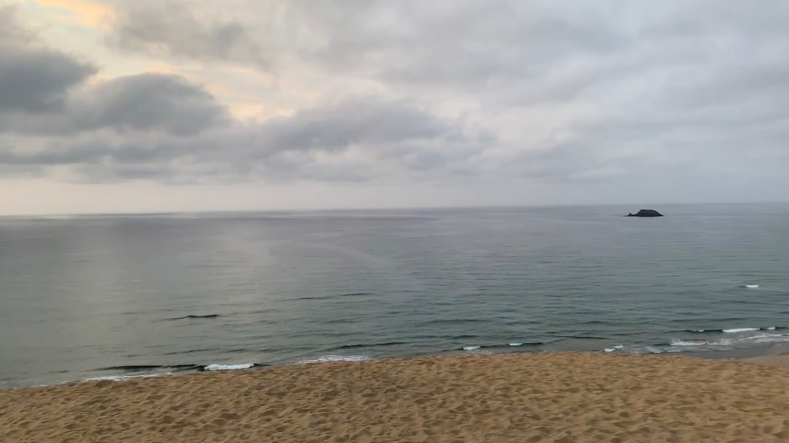 ทิวทัศน์ชายหาดที่มีท้องฟ้ามืดครึ้มและคลื่นสงบ
