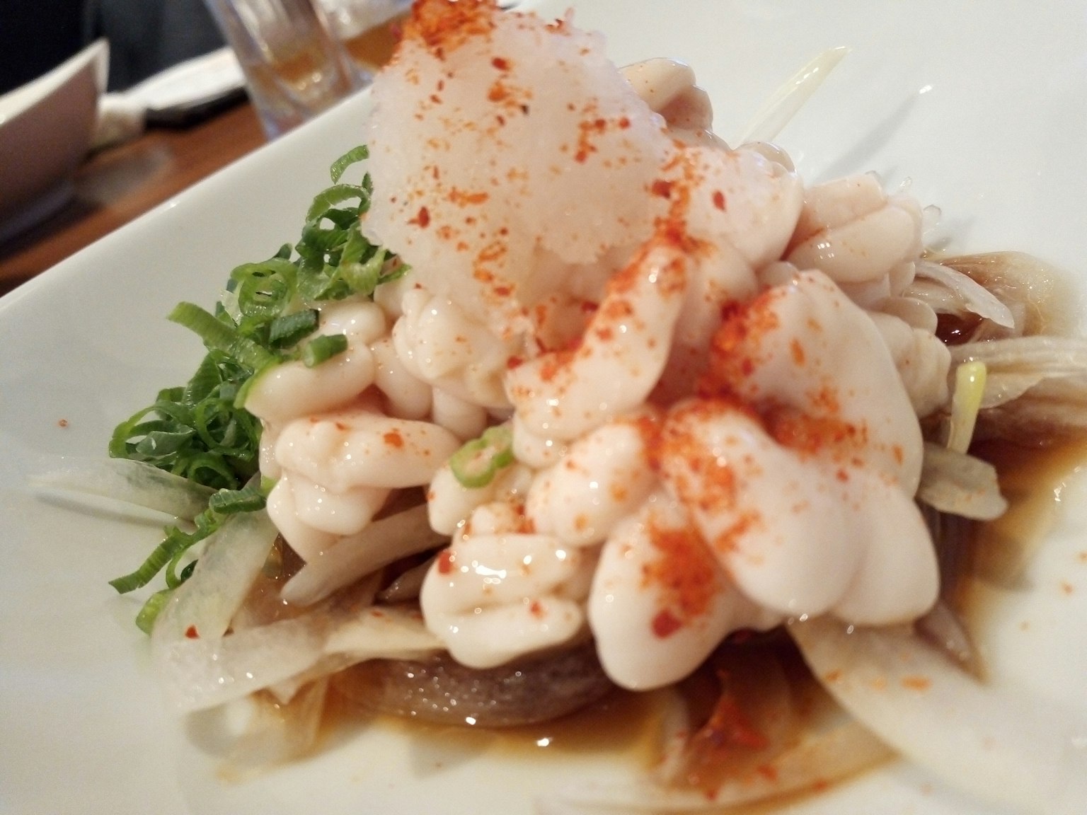 Dish featuring creamy topping with green onions and red spice sprinkled on top