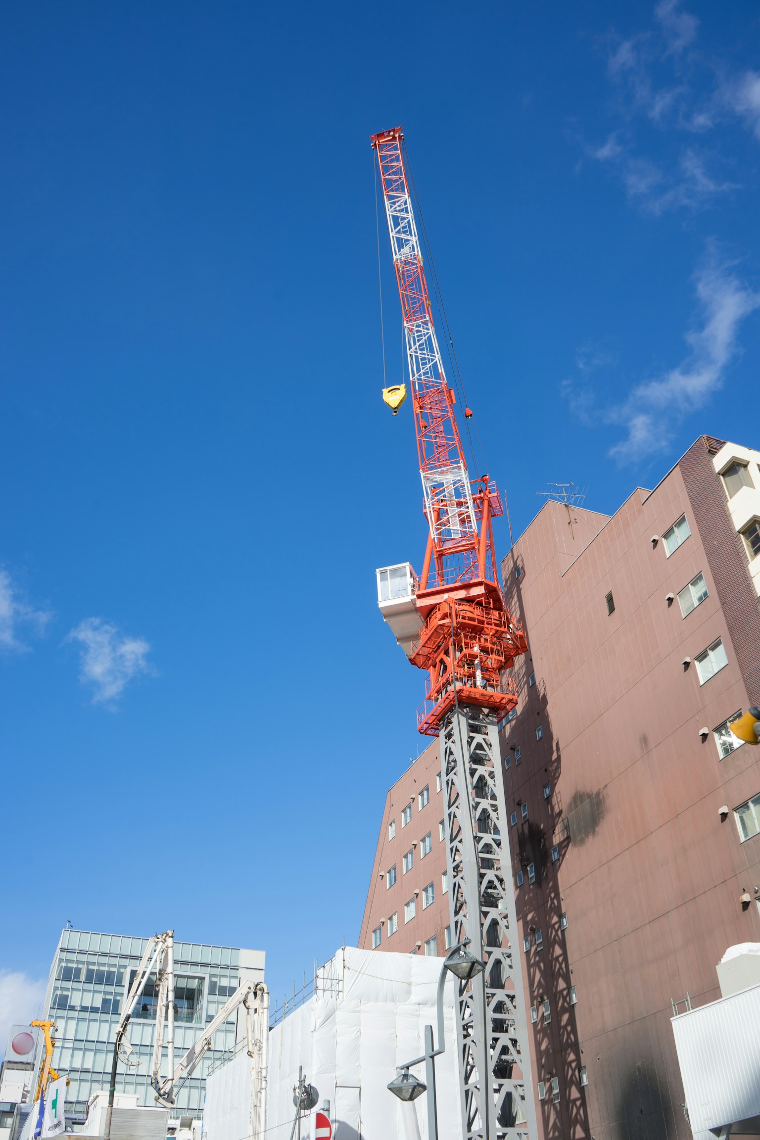 Una alta gru arancione e blu contro un cielo blu chiaro con edifici