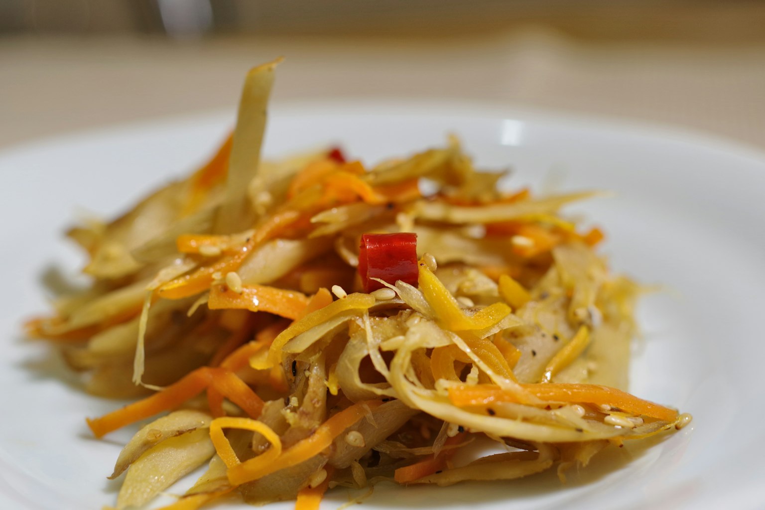 Geriebener Gemüsesalat auf einem Teller mit rotem Chili und orangefarbener Karotte