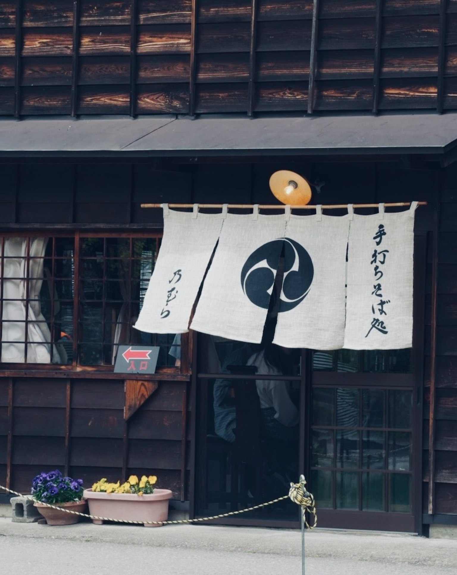 Eingang eines traditionellen japanischen Ladens mit einem weißen Noren und einem schwarzen Symbol