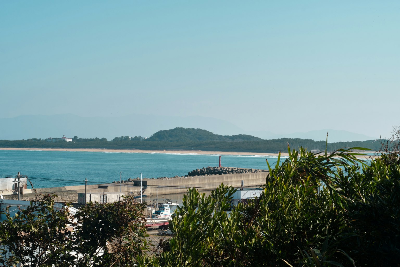 Coastal view featuring a harbor surrounded by hills and clear blue sky