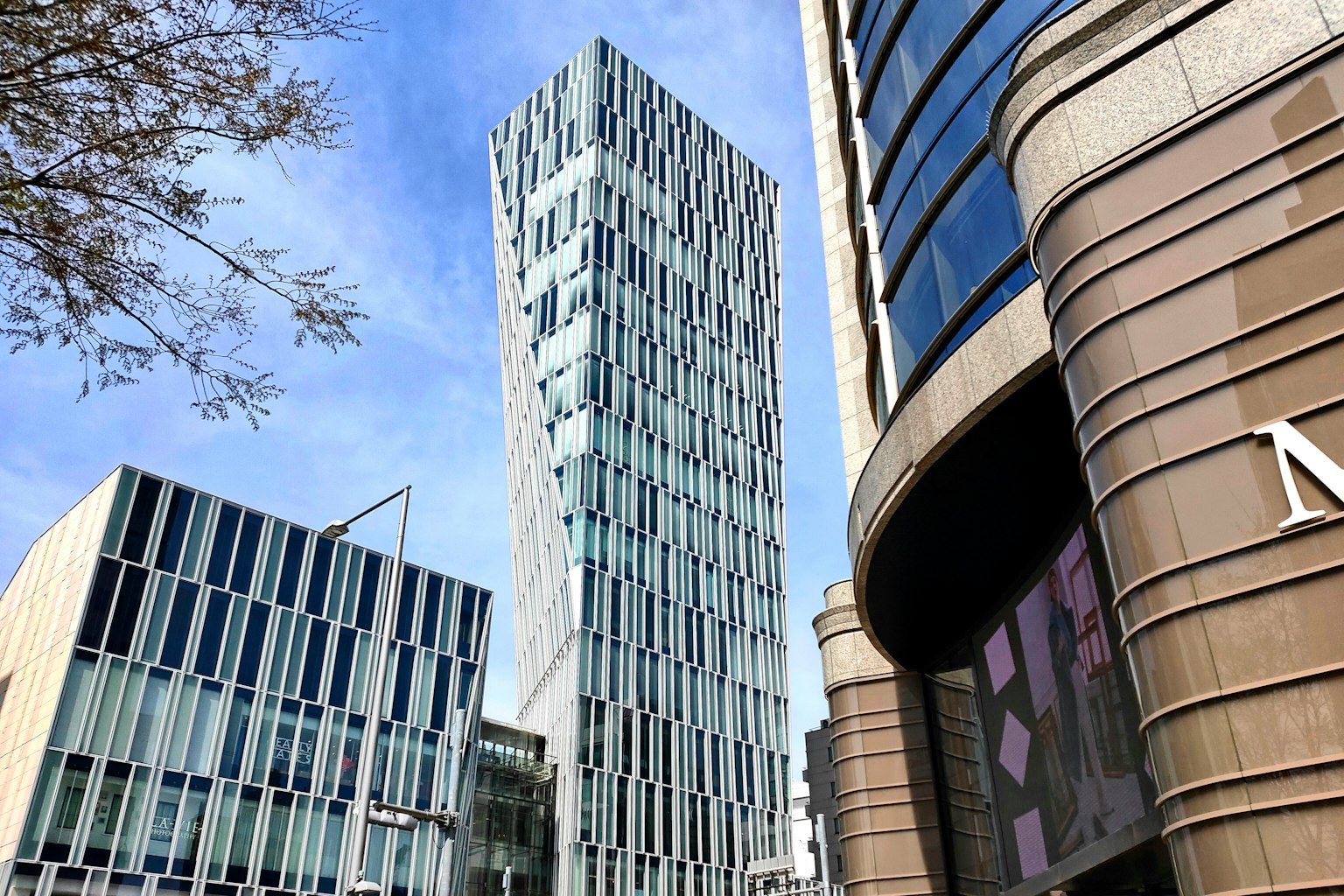 Moderner Wolkenkratzer mit einzigartiger Glasfassade neben zeitgenössischen Gebäuden