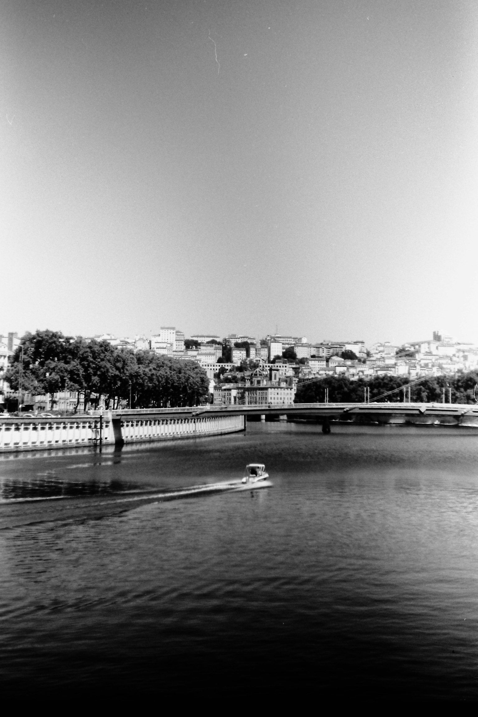 Scena di fiume in bianco e nero Barca che scivola sull'acqua Ponte e skyline della città sullo sfondo