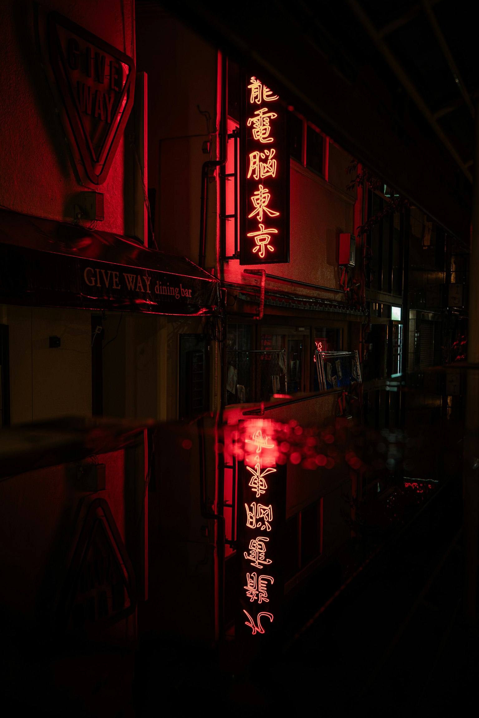 Angolo di strada notturno con riflessi di insegne al neon rosse