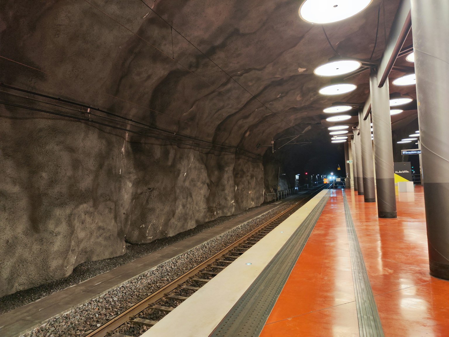 Plateforme de station de métro avec des murs texturés comme de la roche des voies ferrées et un éclairage lumineux