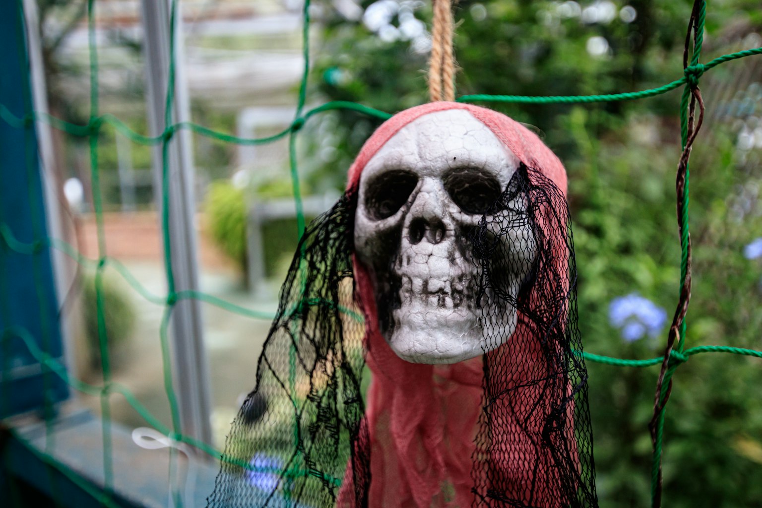 Dekorative Figur mit einem Totenkopfgesicht, das an einem grünen Netz hängt