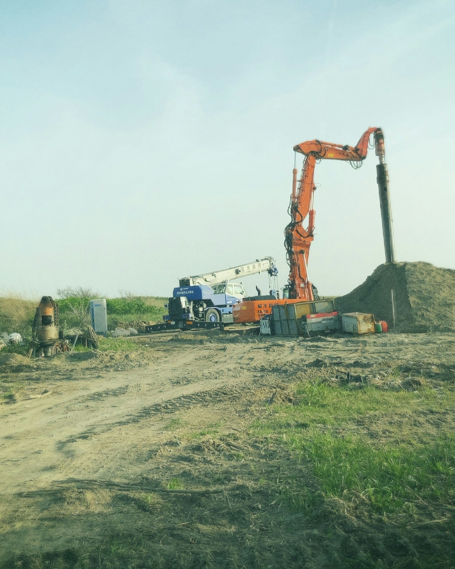 Situs konstruksi dengan crane oranye menggali tanah