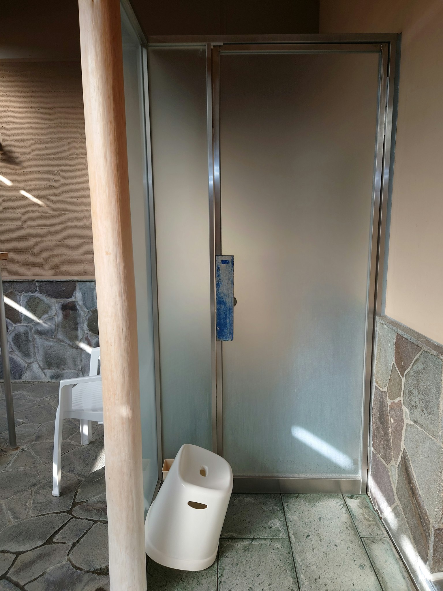 Badezimmer-Ecke mit milchiger Duschkabine und Steinwand