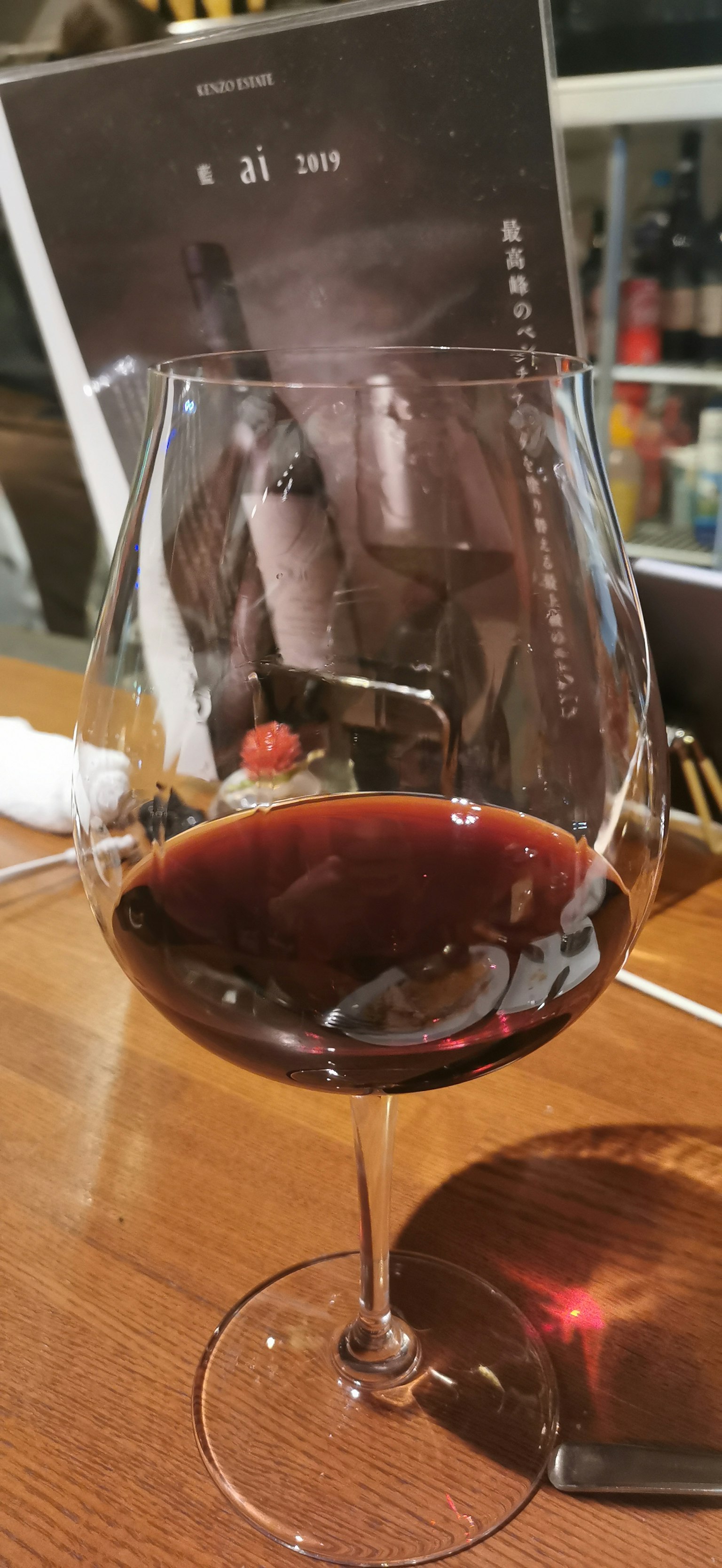 Un bicchiere di vino rosso su un tavolo con un menu sullo sfondo