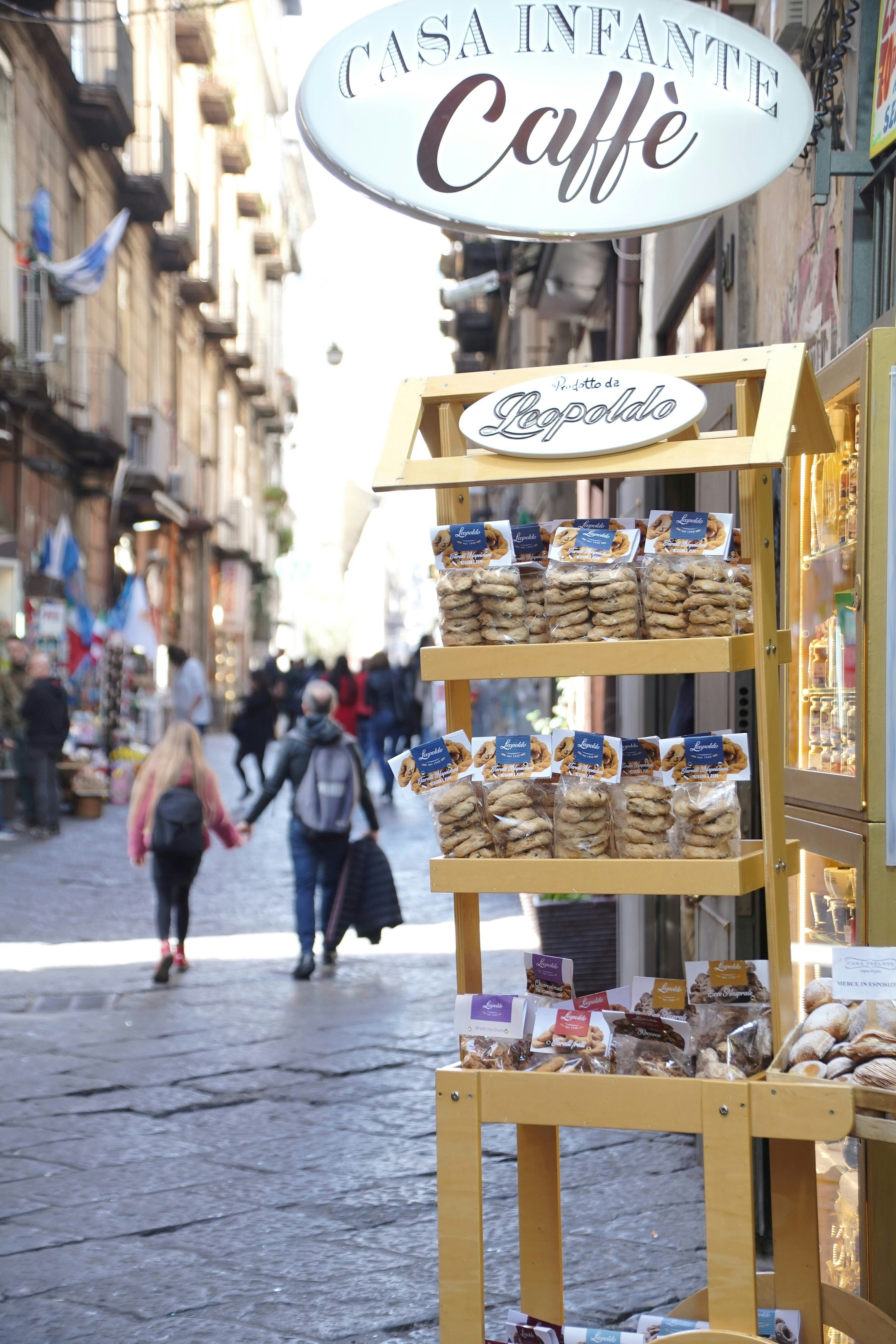 callejón de Nápoles con letrero de cafetería y exhibición de souvenirs