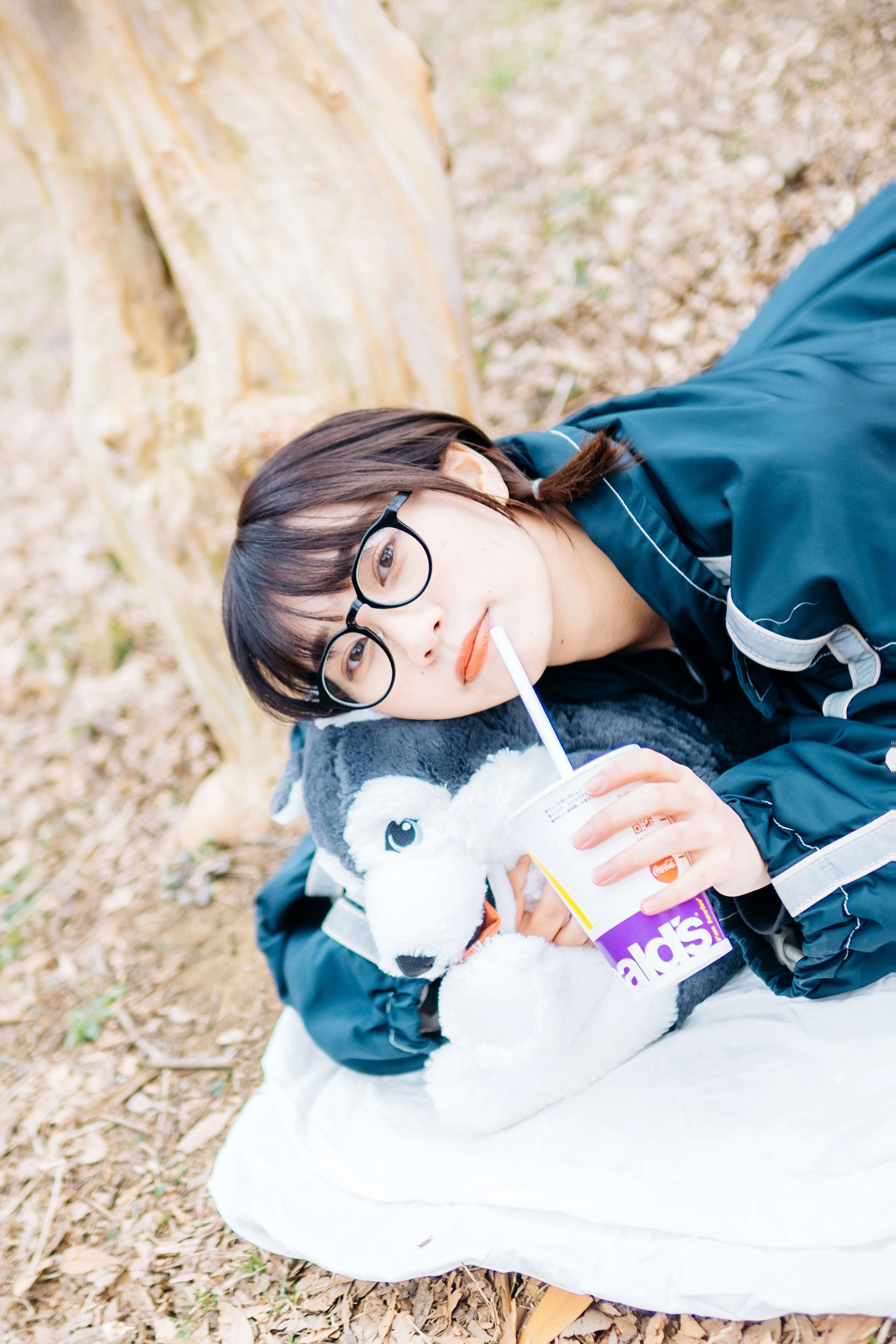 芝生の上でぬいぐるみを抱えるメガネの子ども