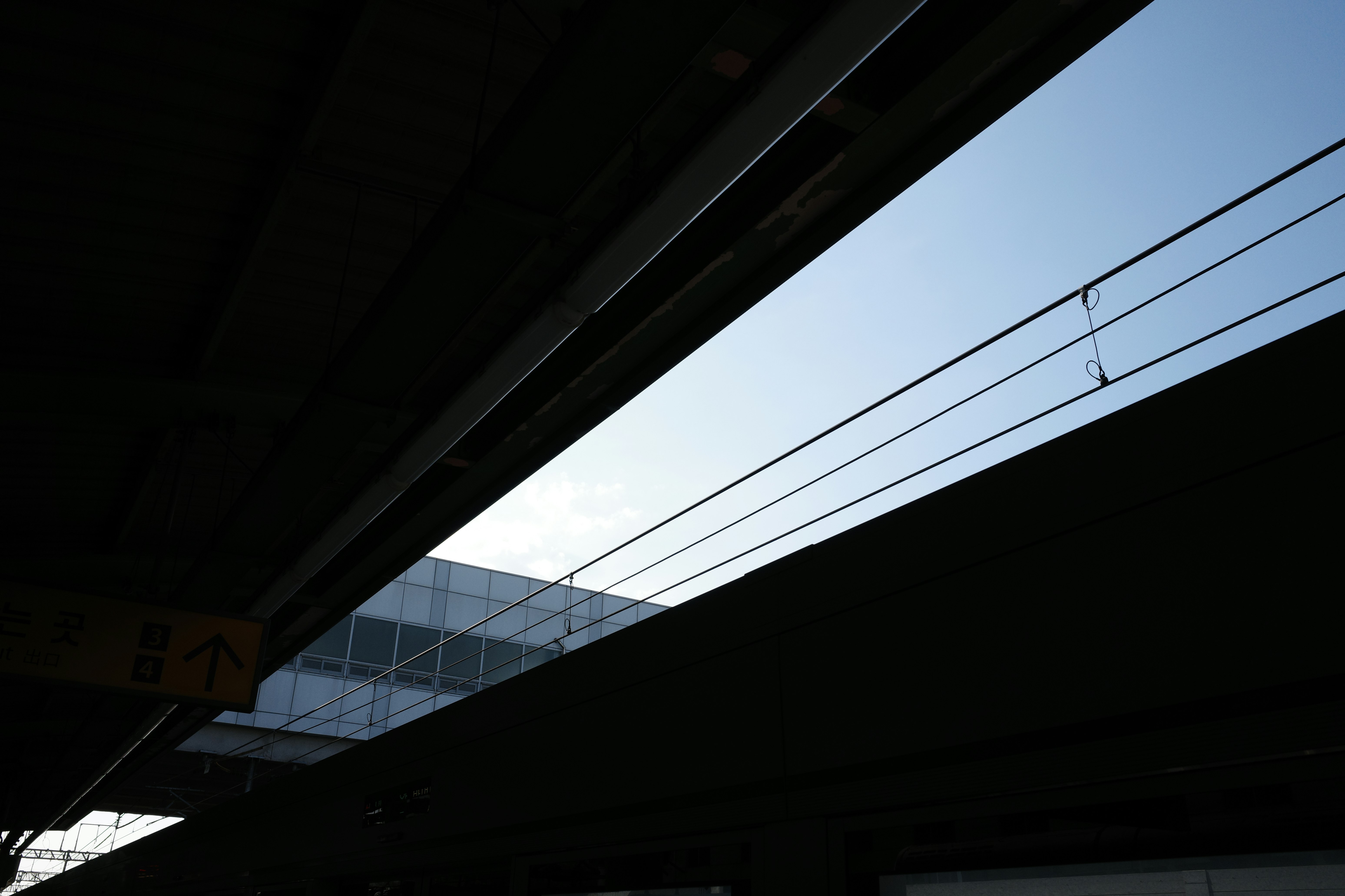 View of overhead power lines and blue sky from under an elevated structure