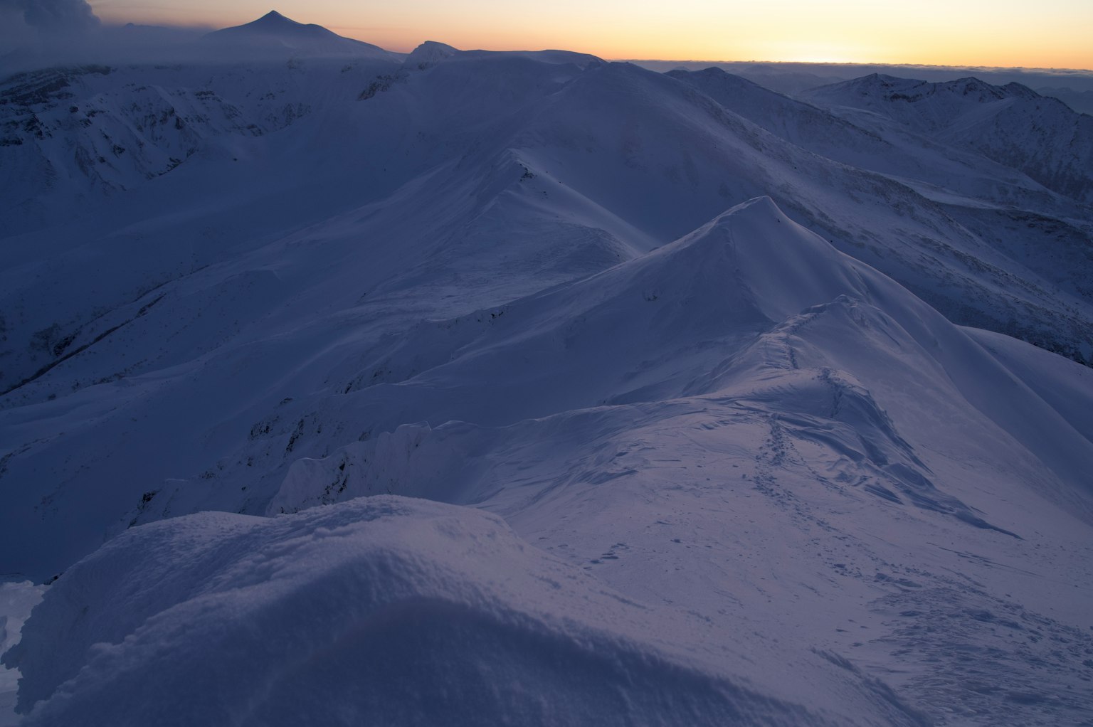 Weitläufige Aussicht auf schneebedeckte Berge bei Sonnenuntergang