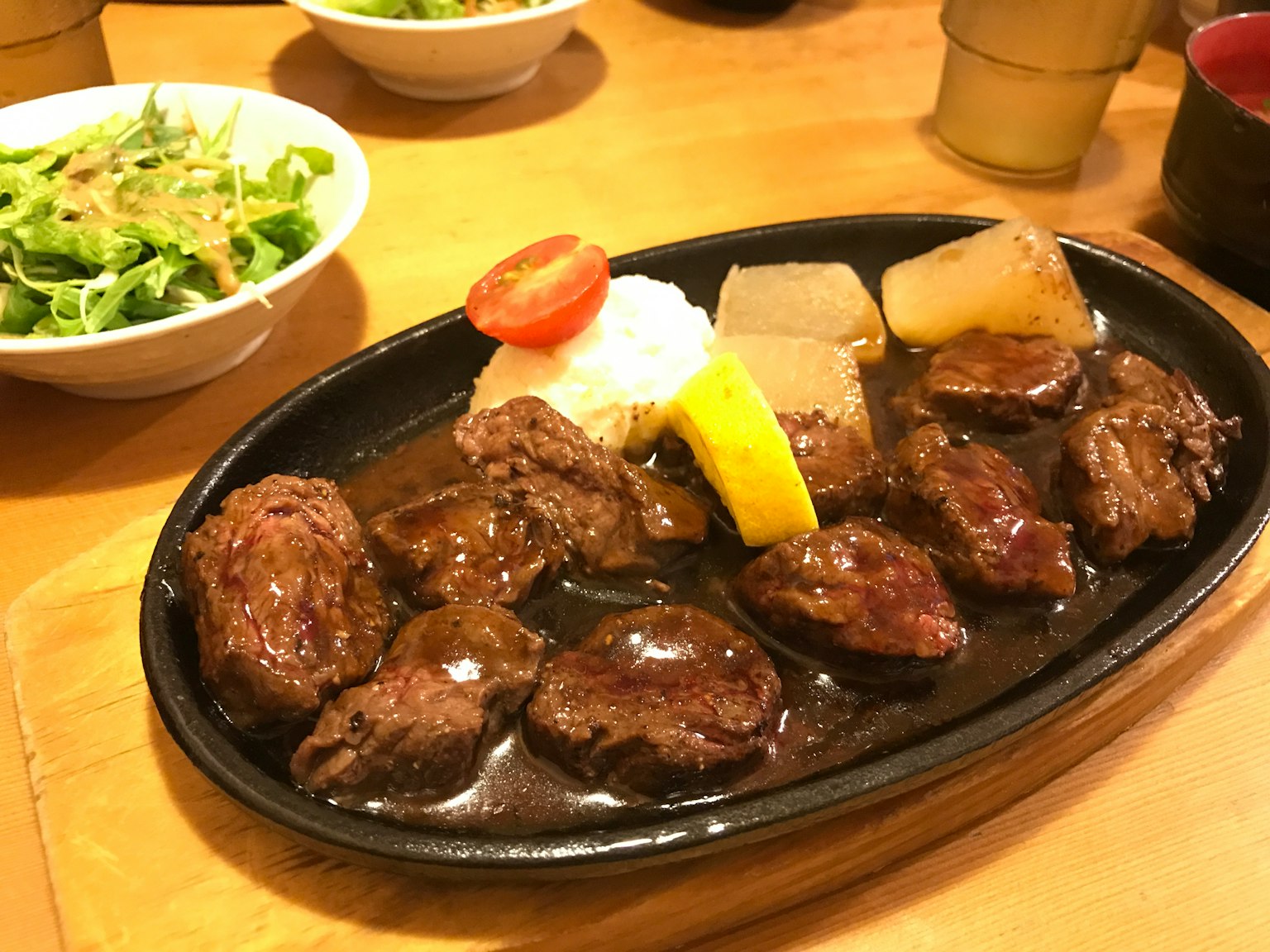 Steak de boeuf crépitant servi sur une assiette chaude avec des légumes et une salade